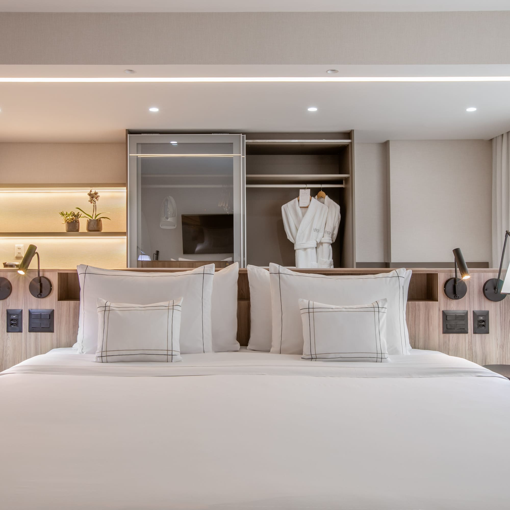 a bed with white pillows and a white robe on the wall