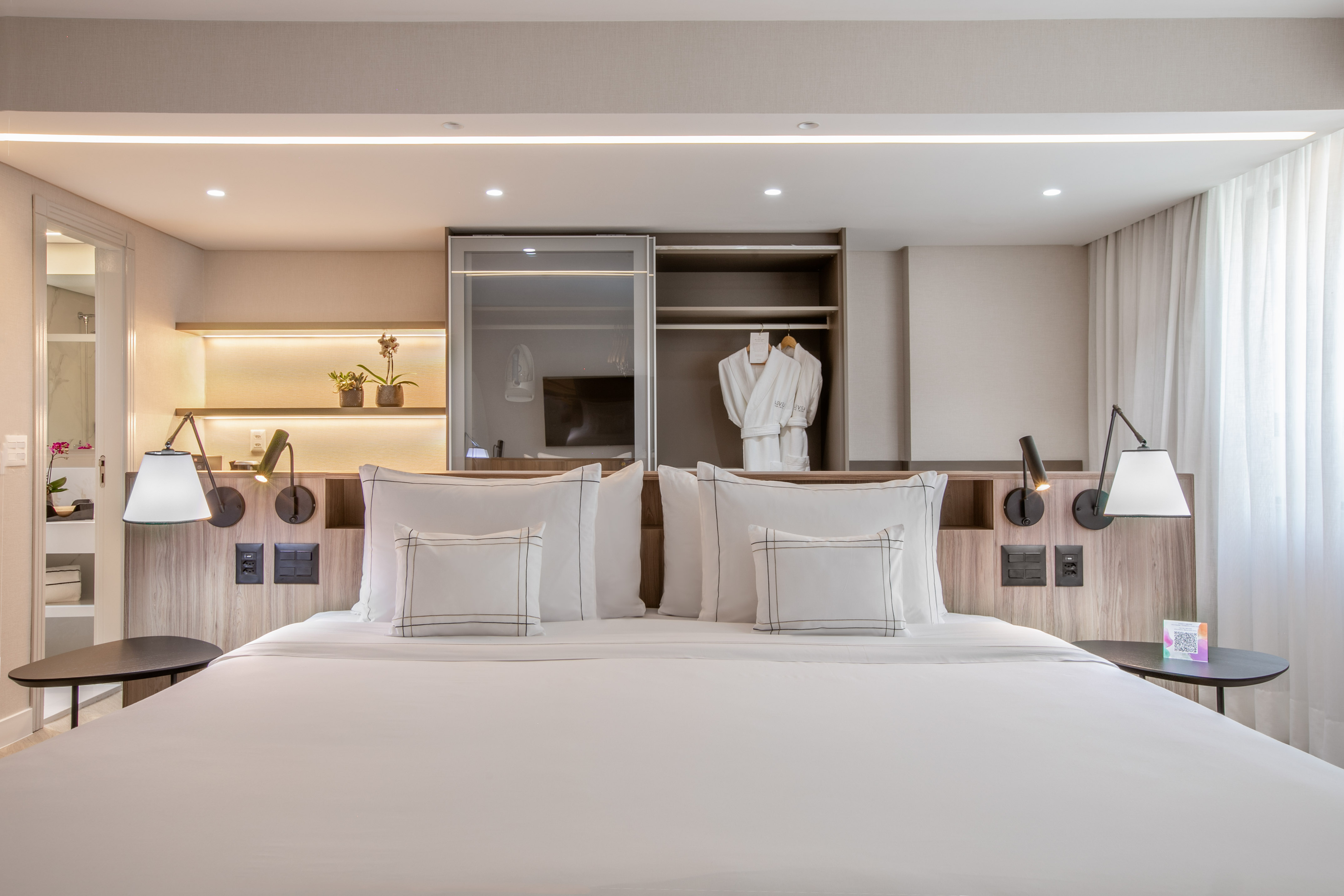 Modern hotel room with king bed, built-in closet, and ambient lighting.