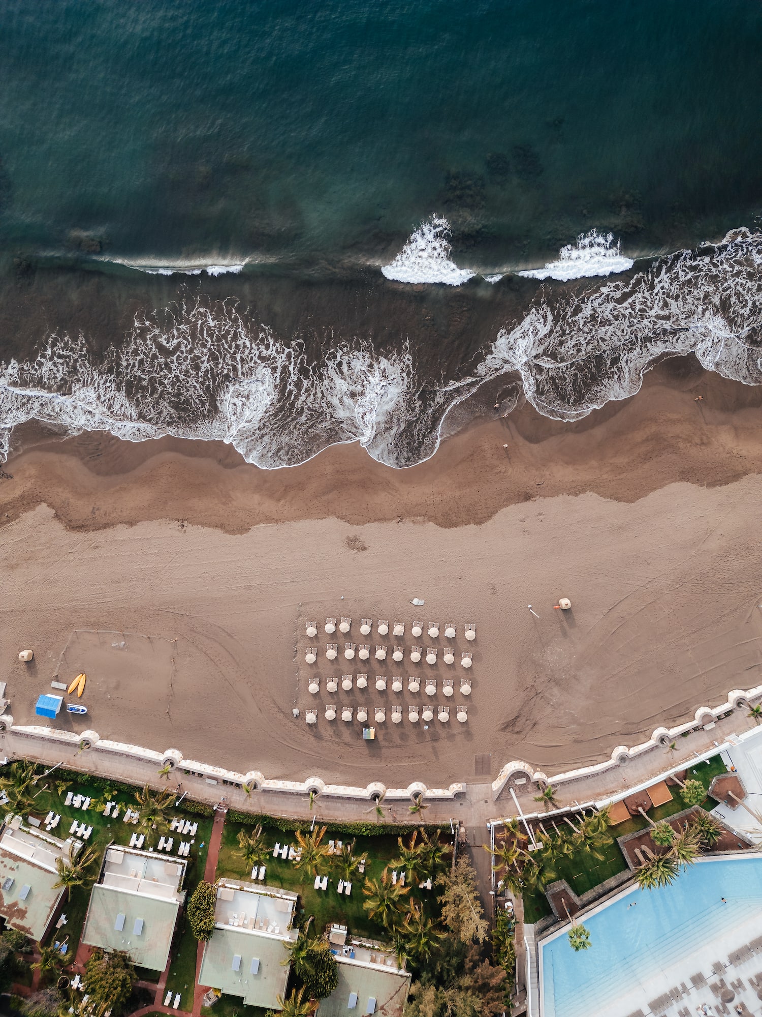 an aerial view of a beach with umbrellas and chairs