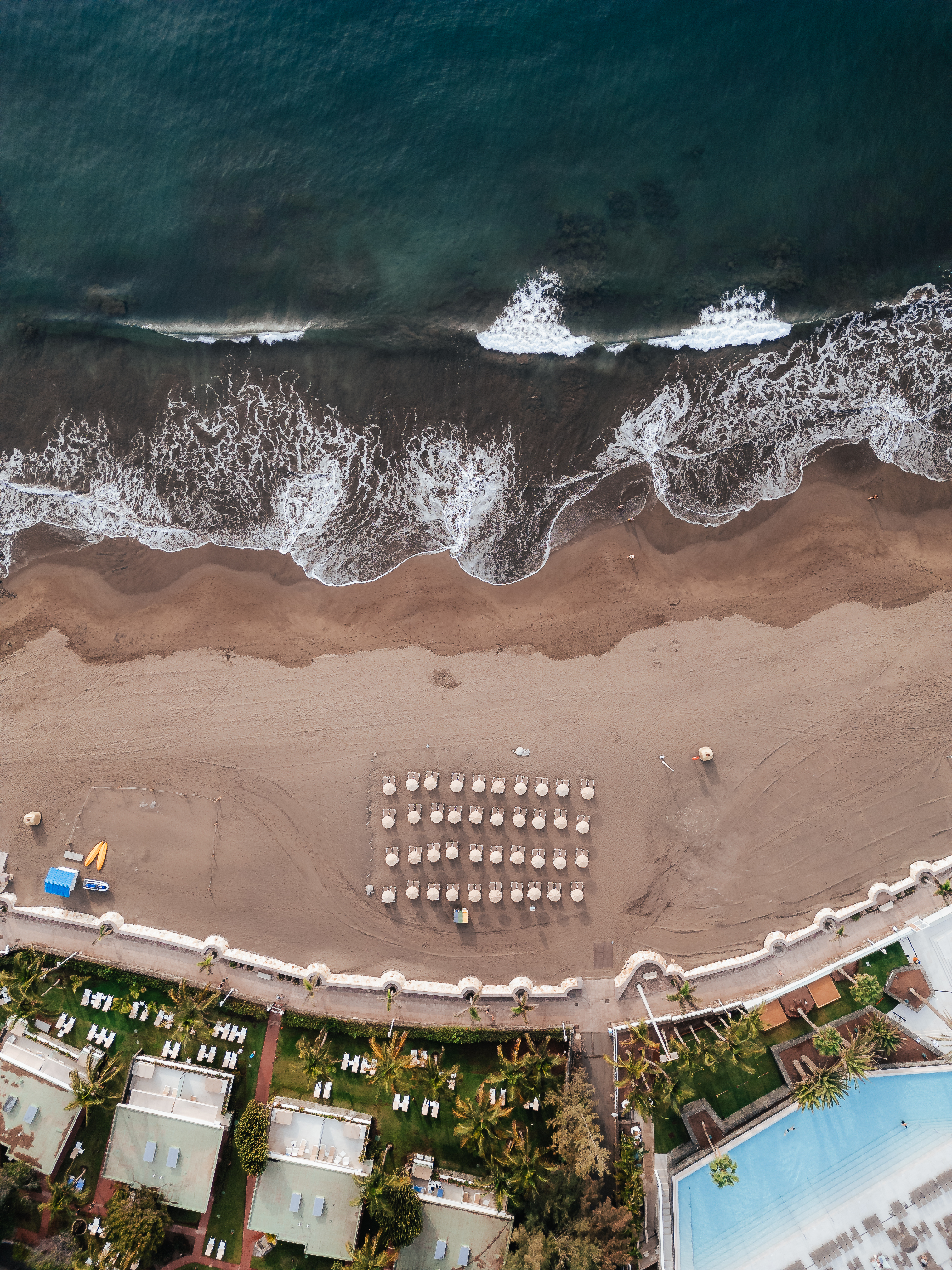 an aerial view of a beach with umbrellas and chairs