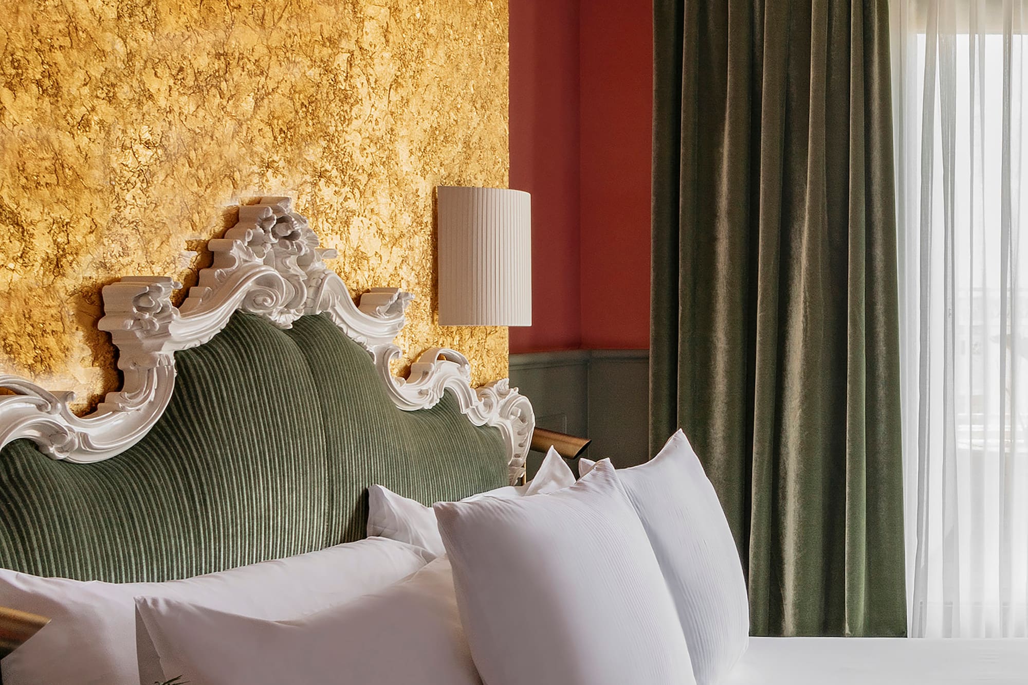 a bed with white pillows and a lamp in a room with a gold wall
