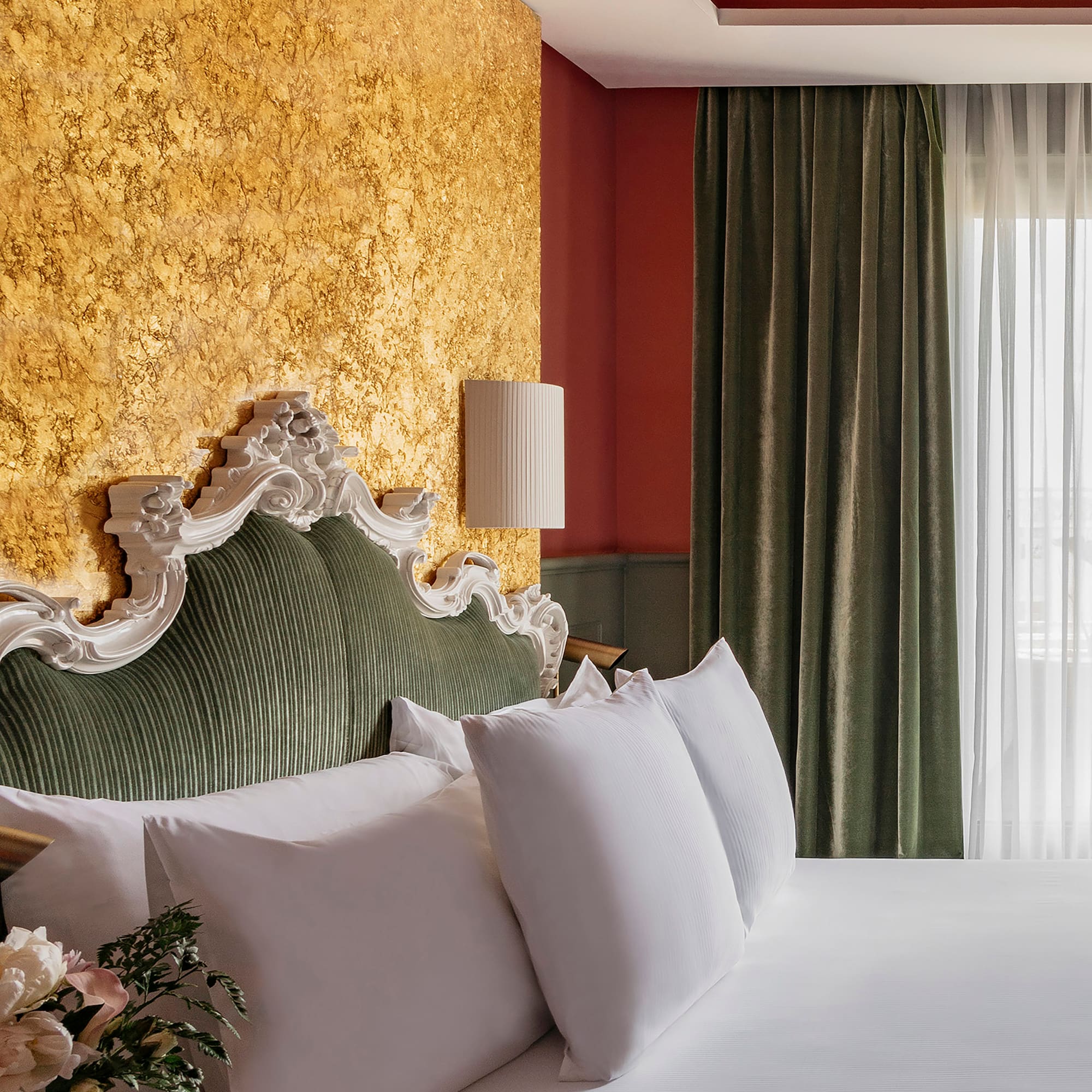 a bed with white pillows and a lamp in a room with a gold wall