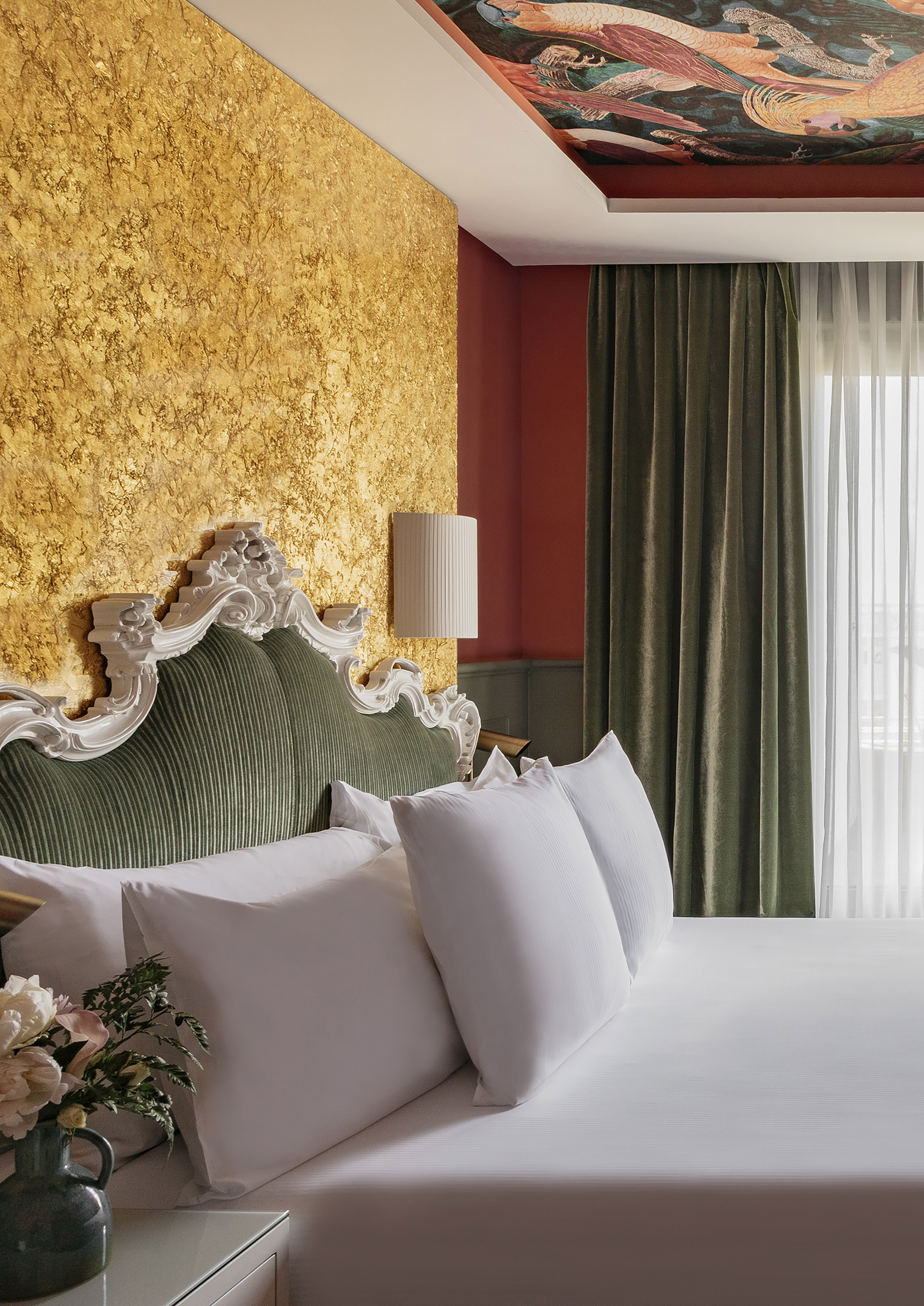 a bed with white pillows and a lamp in a room with a gold wall