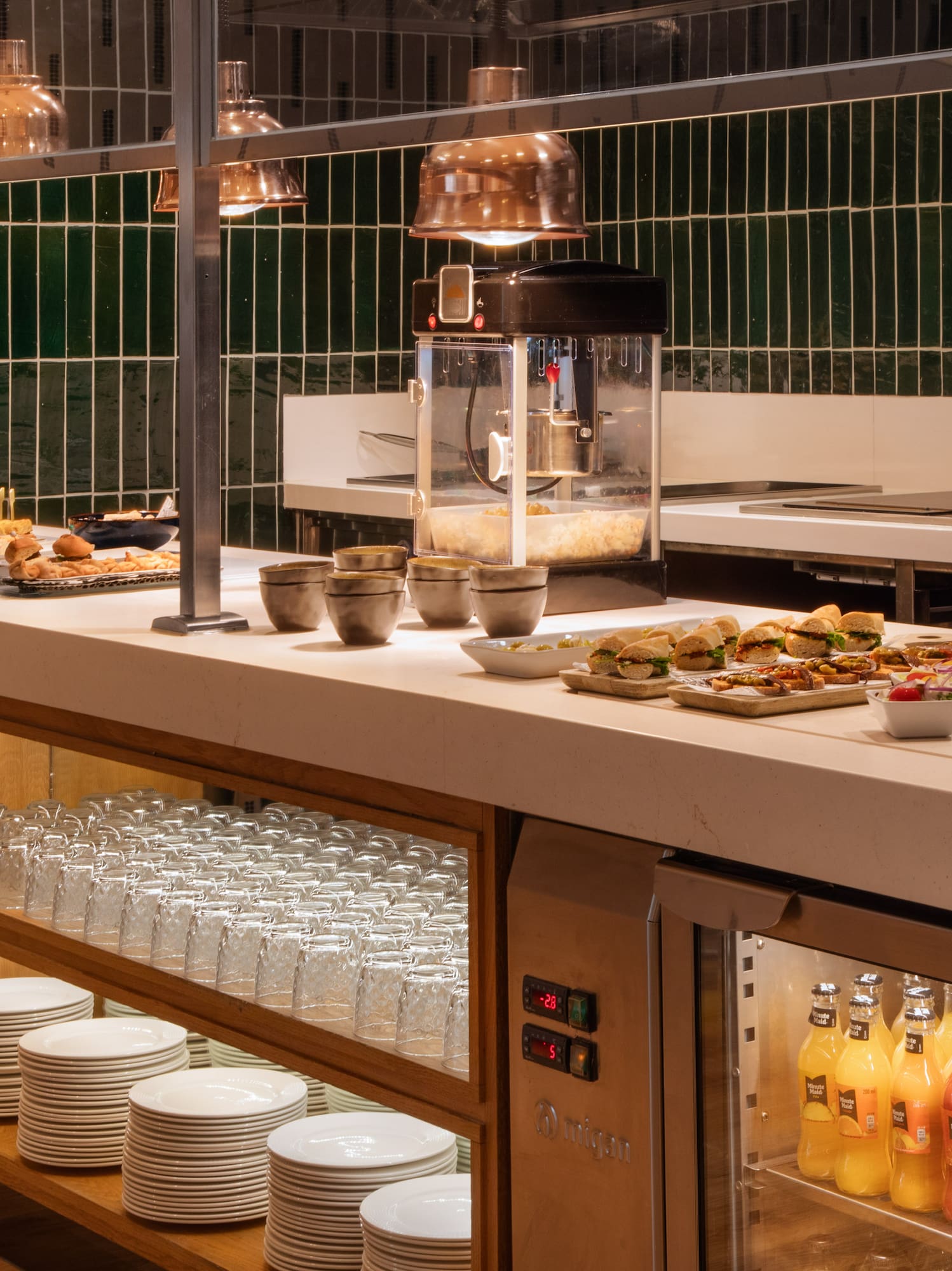 Self-serve hotel buffet with snacks, mini sandwiches, cold drinks, and popcorn machine.