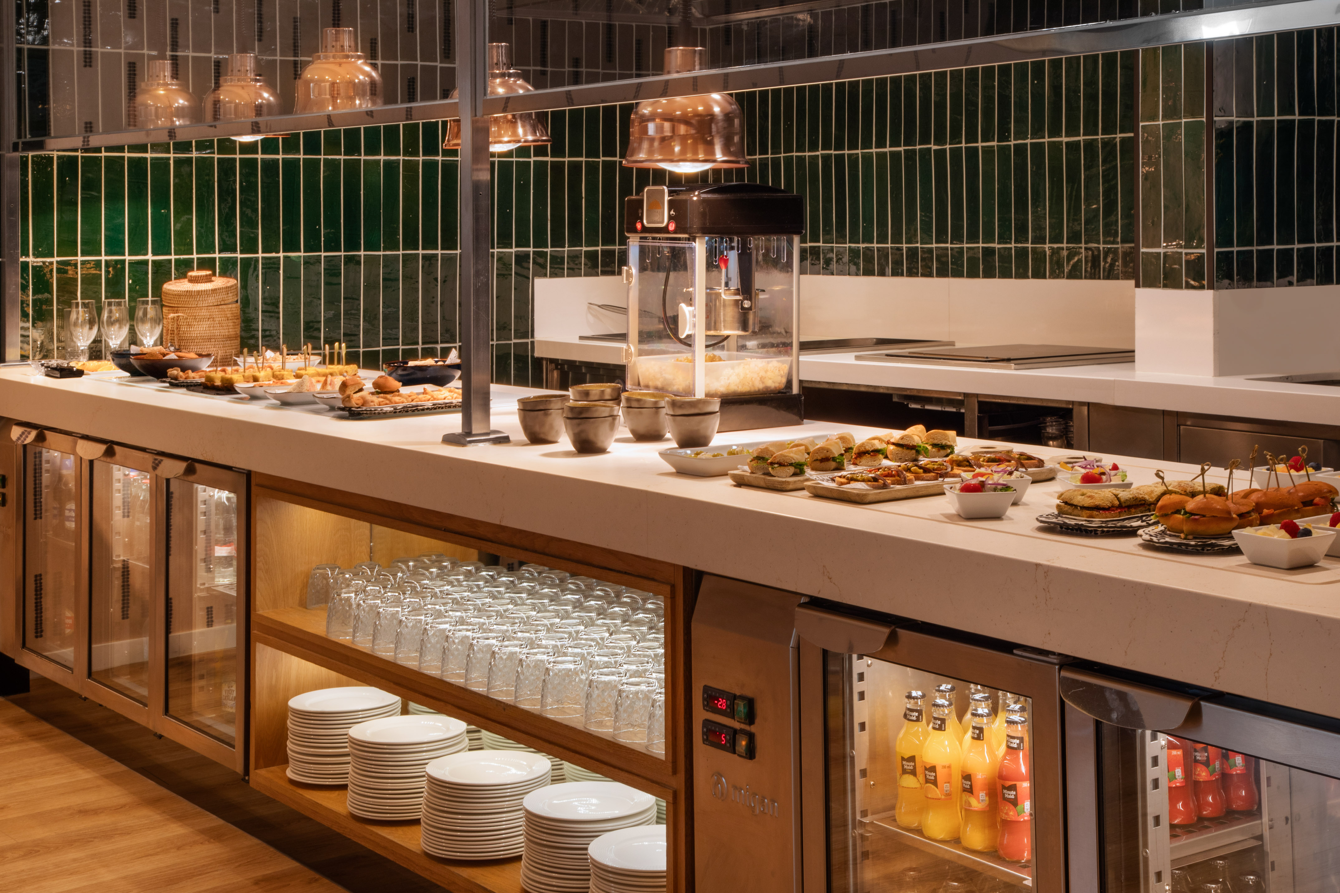 Self-serve hotel buffet with snacks, mini sandwiches, cold drinks, and popcorn machine.