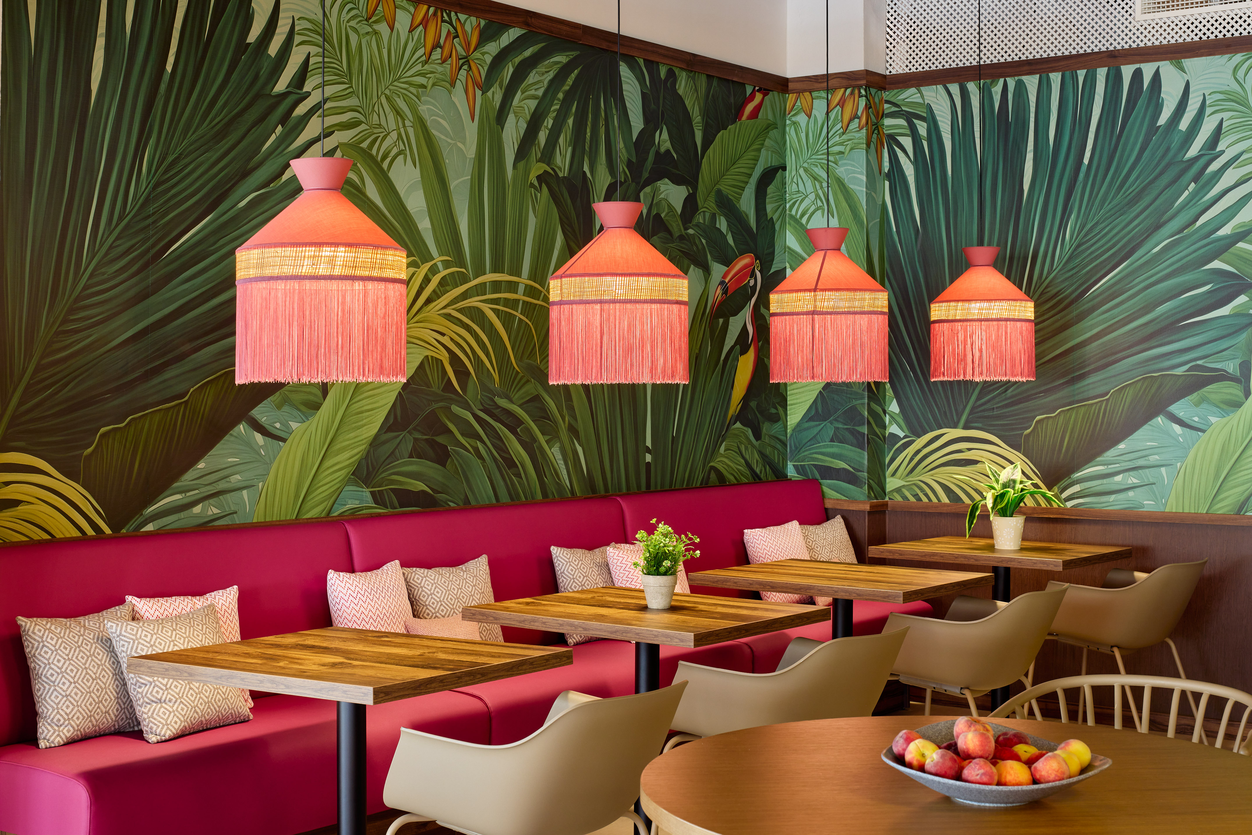 Tropical cafe with jungle wallpaper, fuchsia booths, pink fringe lamps.