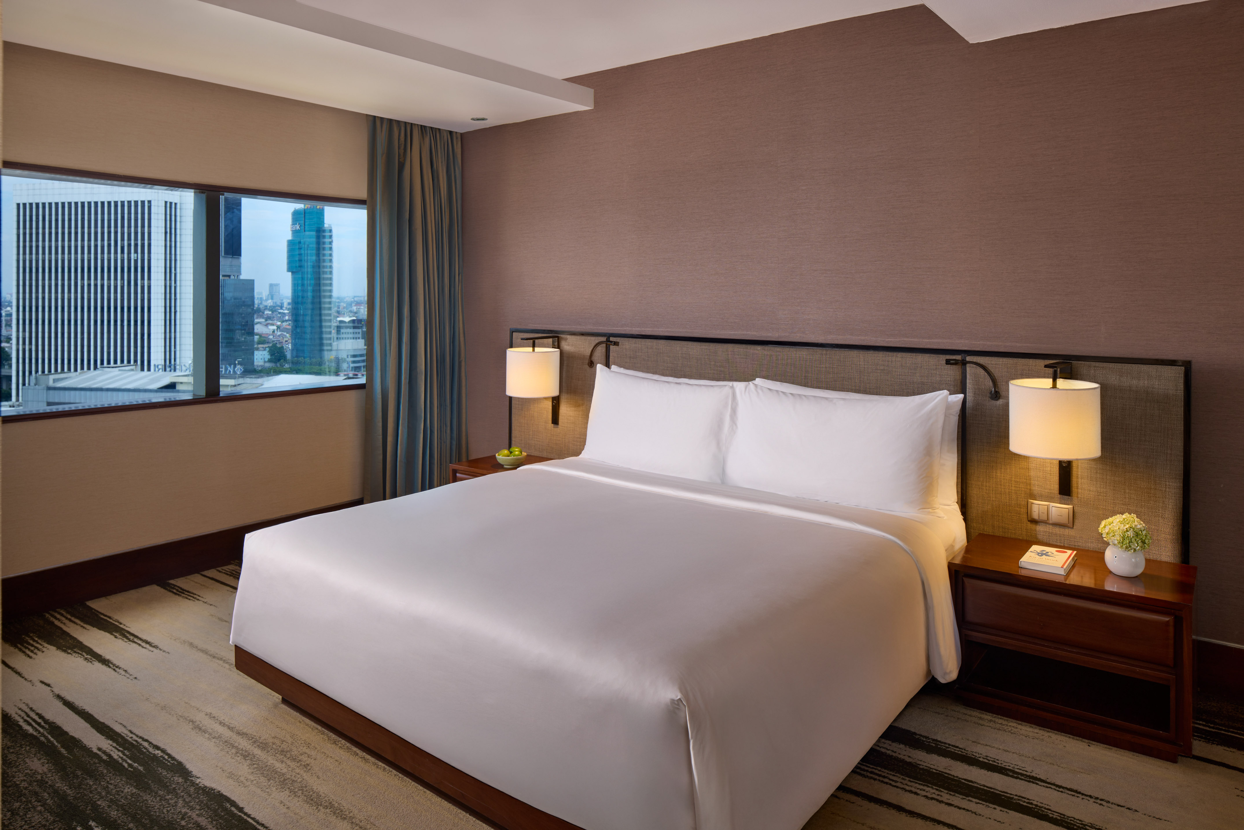 Luxury hotel room with king bed, city view window, and modern decor.