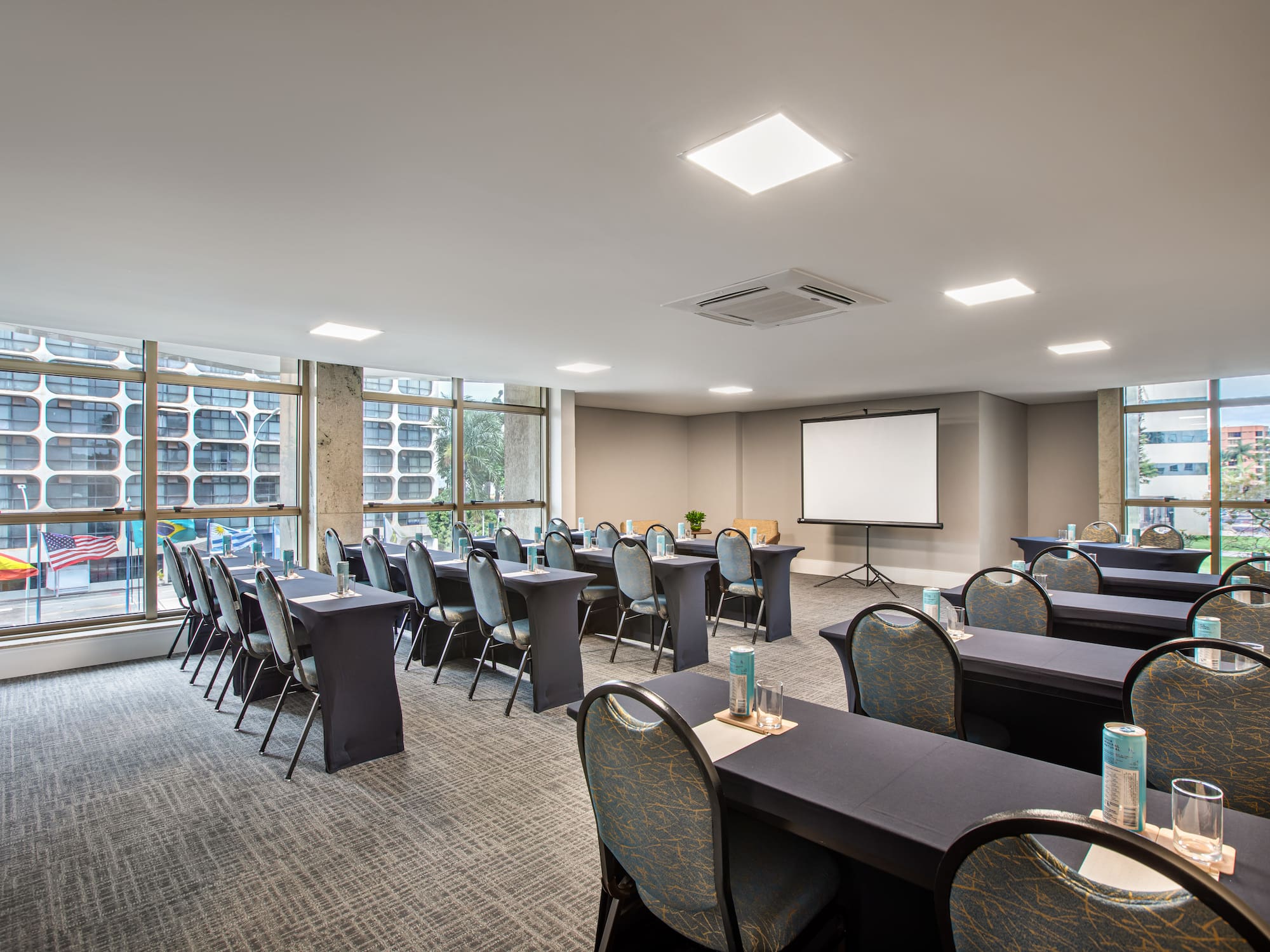 Modern classroom style conference room with projector screen and city view.