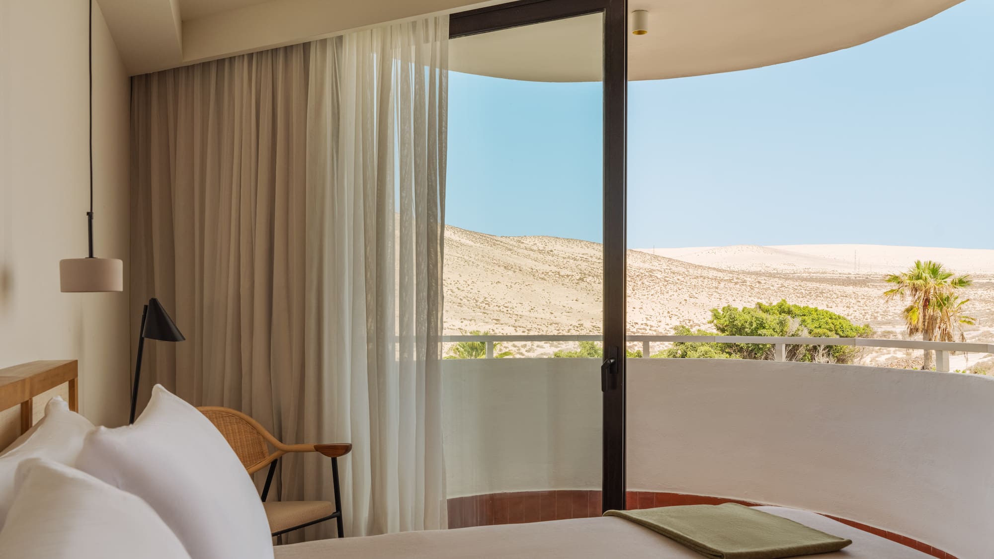a bed with a chair and a chair in a room with a view of the desert