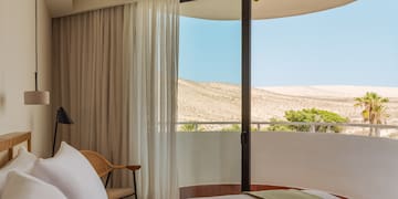 a bed with a chair and a chair in a room with a view of the desert