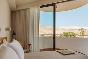 a bed with a chair and a chair in a room with a view of the desert