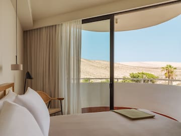 a bed with a chair and a chair in a room with a view of the desert