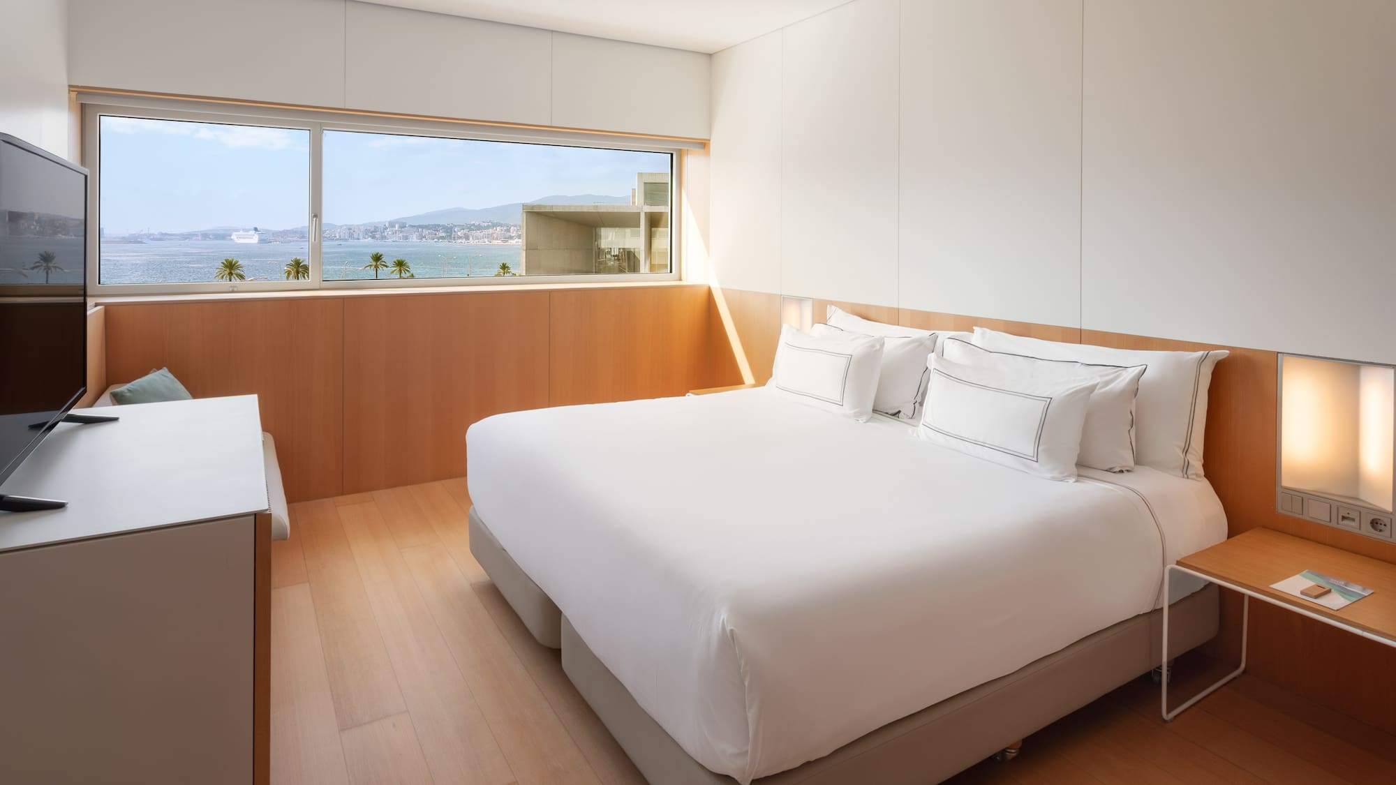 a bedroom with a large window overlooking the water