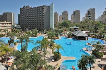 a large pool with palm trees and buildings in the background
