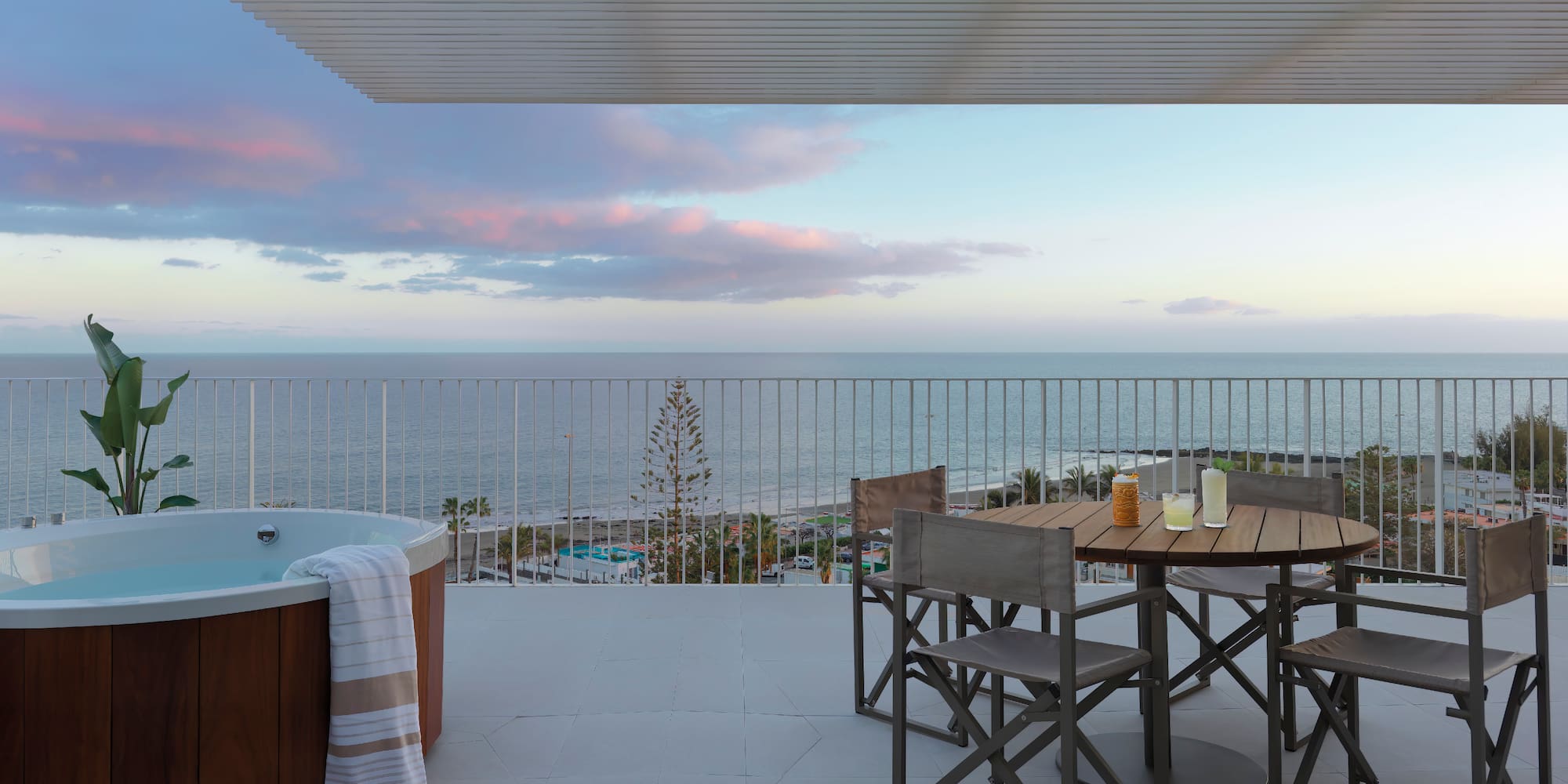 a hot tub with a table and chairs on a deck overlooking the ocean