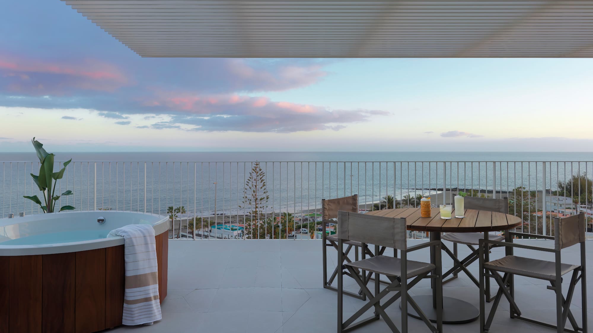 a hot tub with a table and chairs on a deck overlooking the ocean
