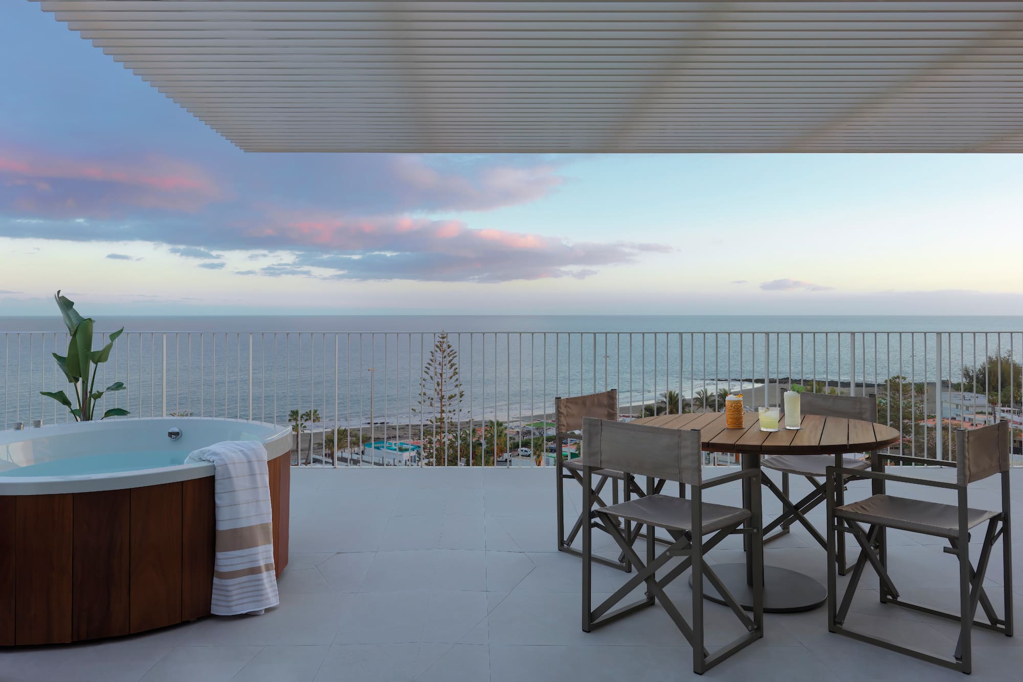 a hot tub with a table and chairs on a deck overlooking the ocean