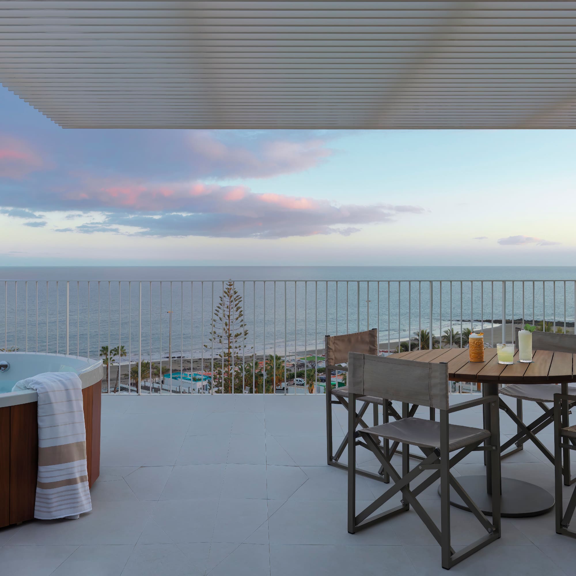 a hot tub with a table and chairs on a deck overlooking the ocean