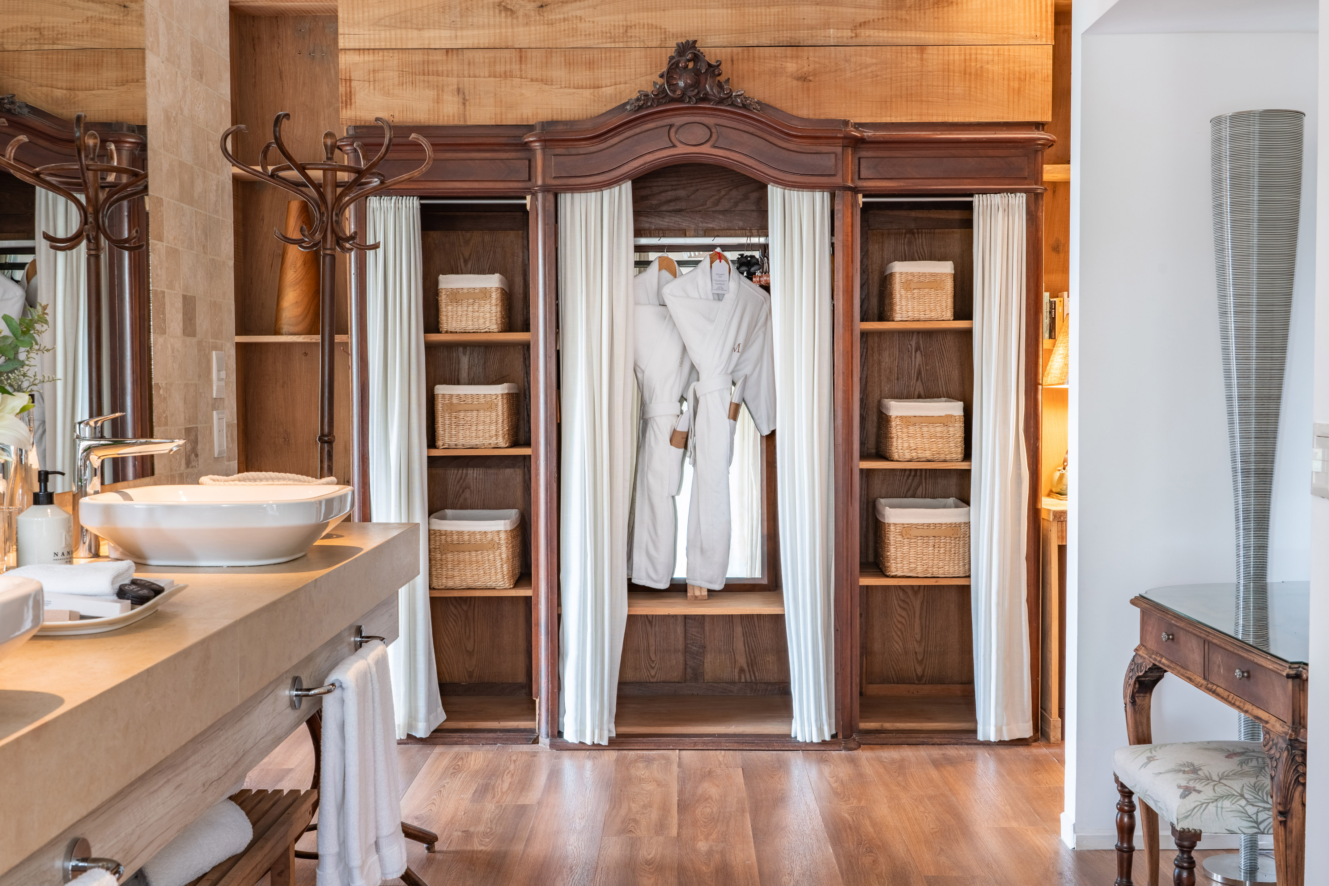 Ornate wooden wardrobe with bathrobes in a luxurious hotel bathroom.