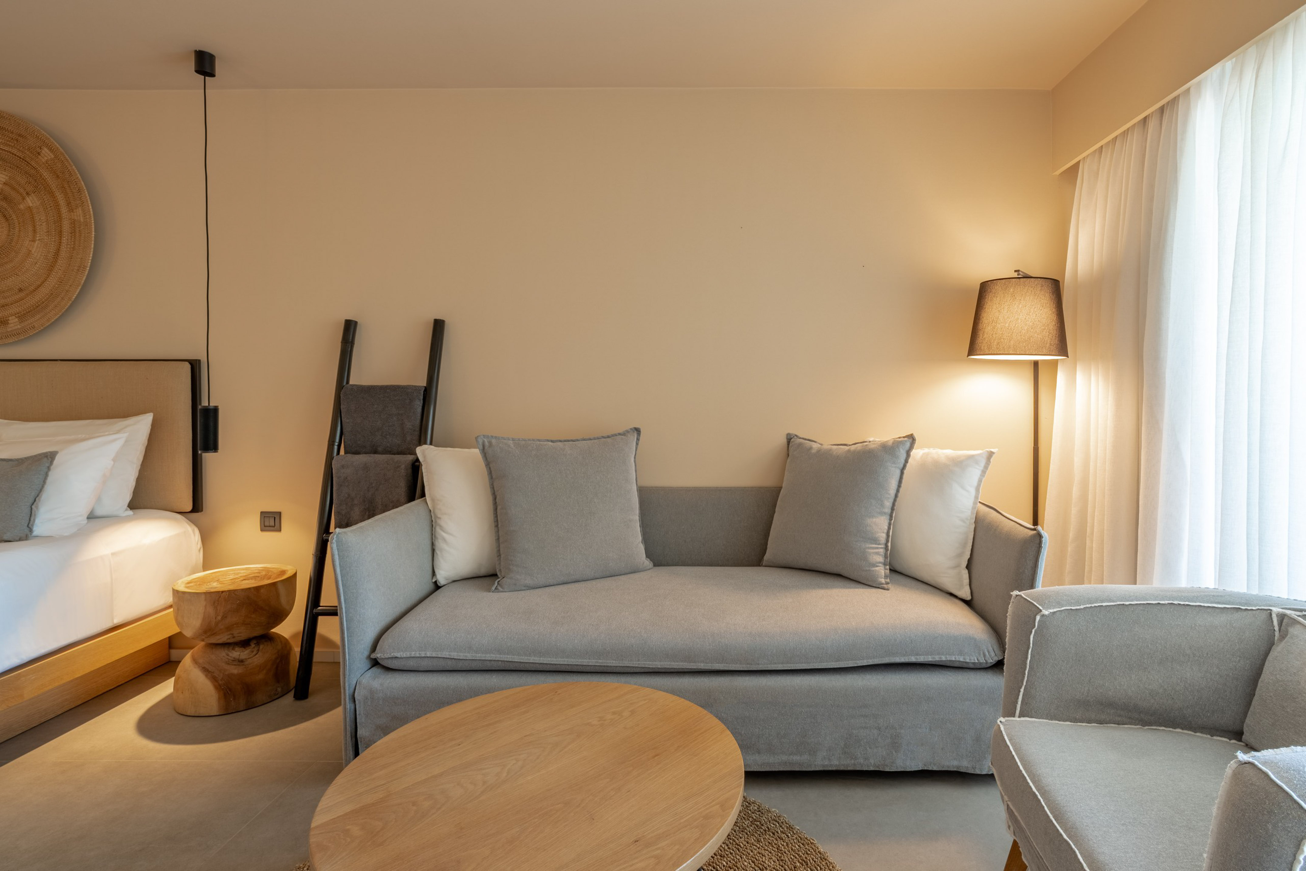 Modern neutral hotel suite with sofa, wooden table, and soft lighting.