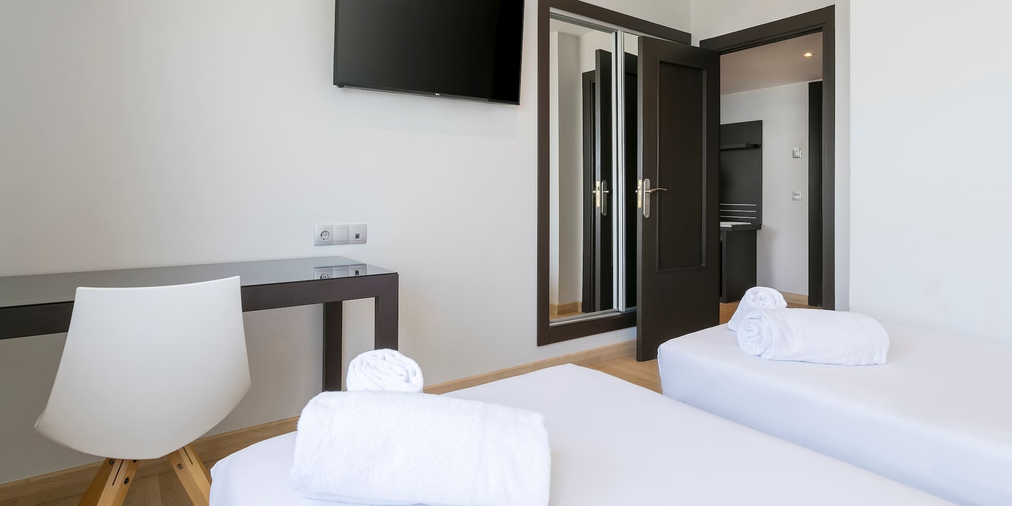 a room with white beds and a tv