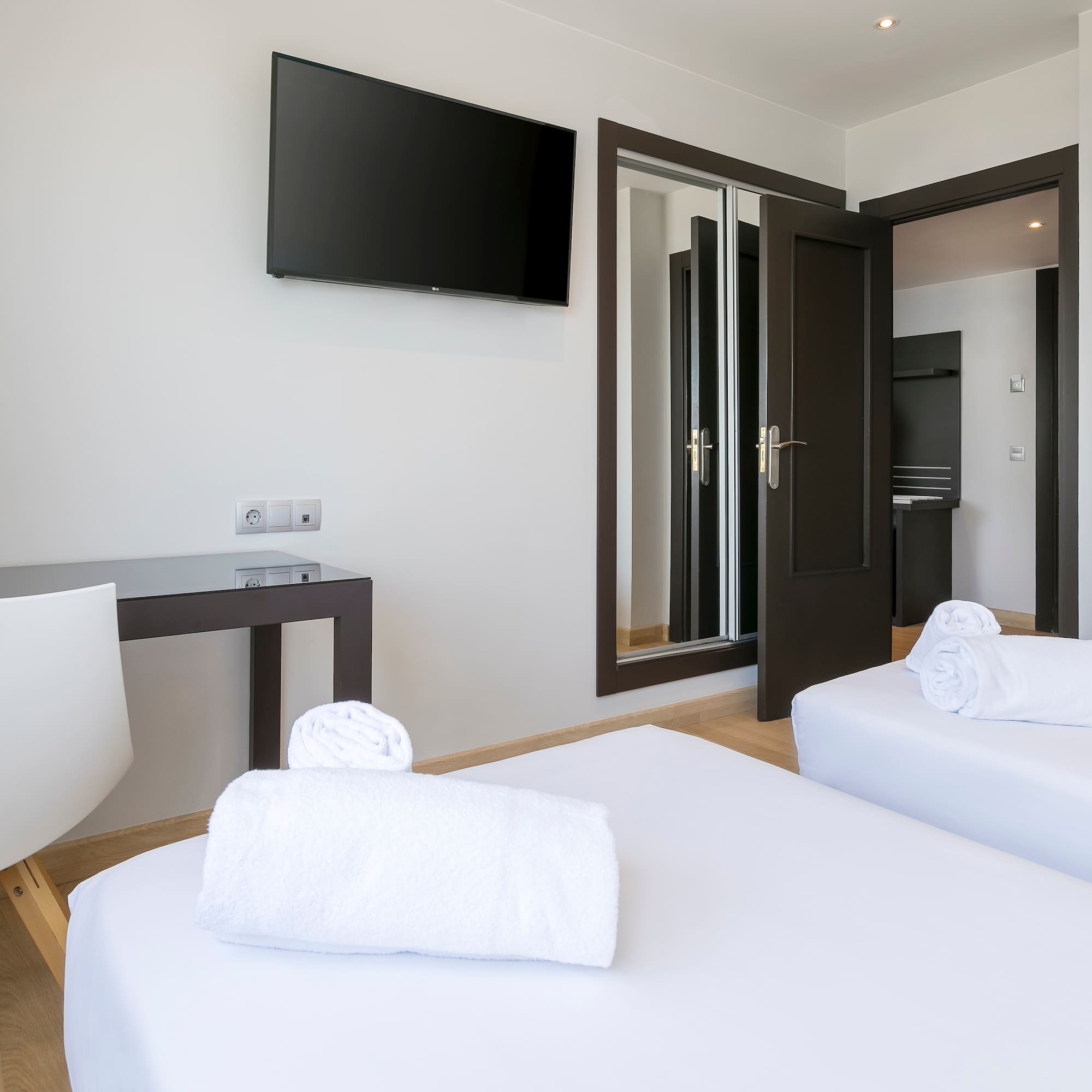 a room with white beds and a tv