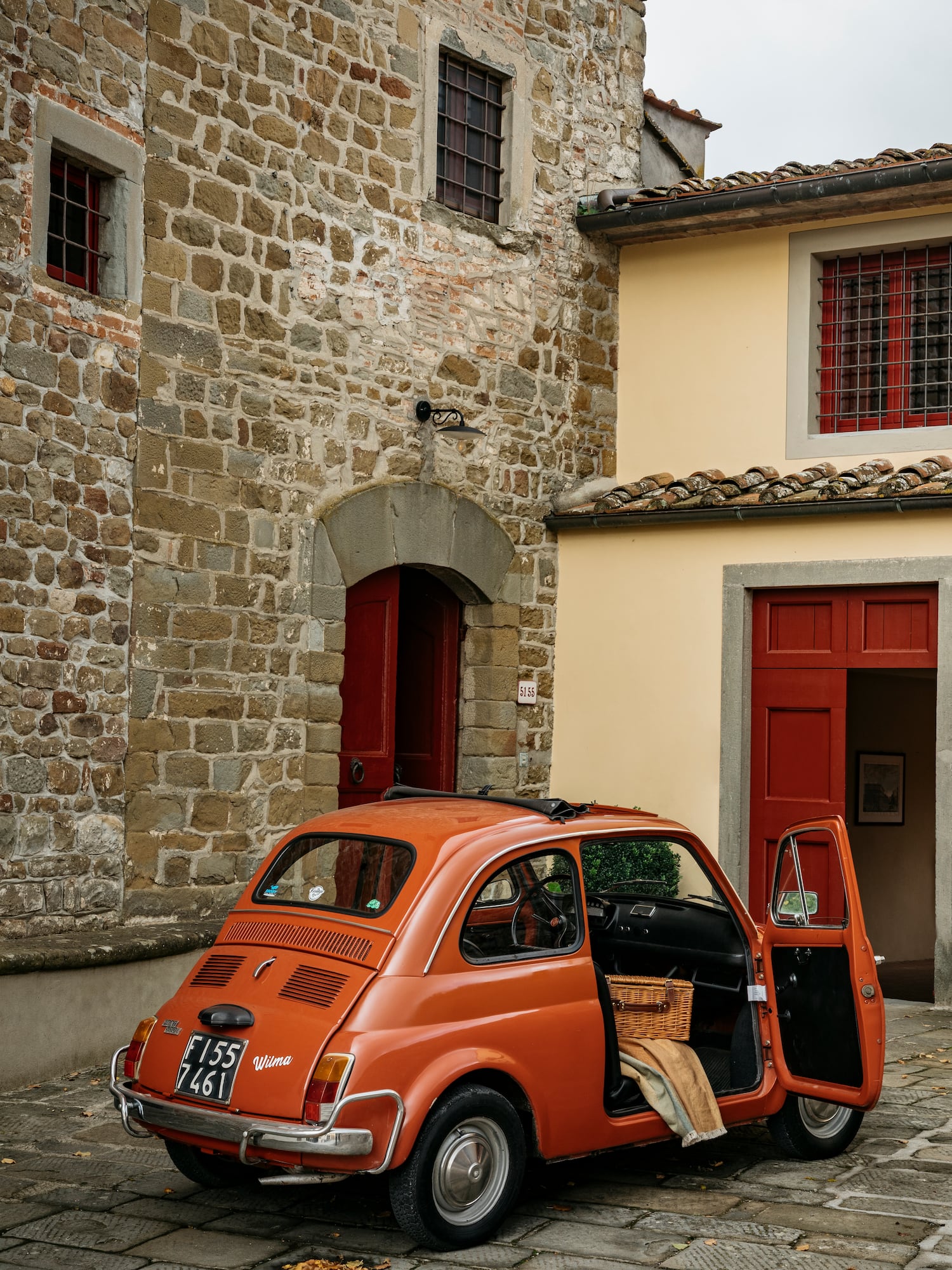 an orange car parked in front of a stone building
