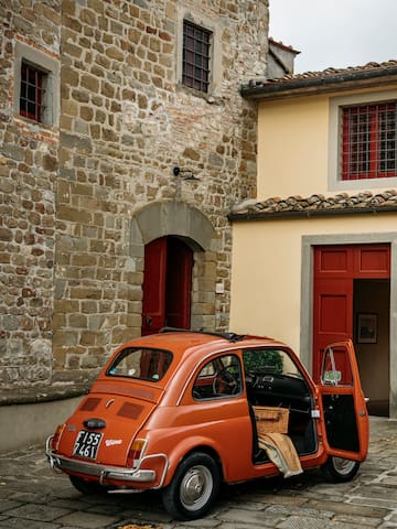 an orange car parked in front of a stone building