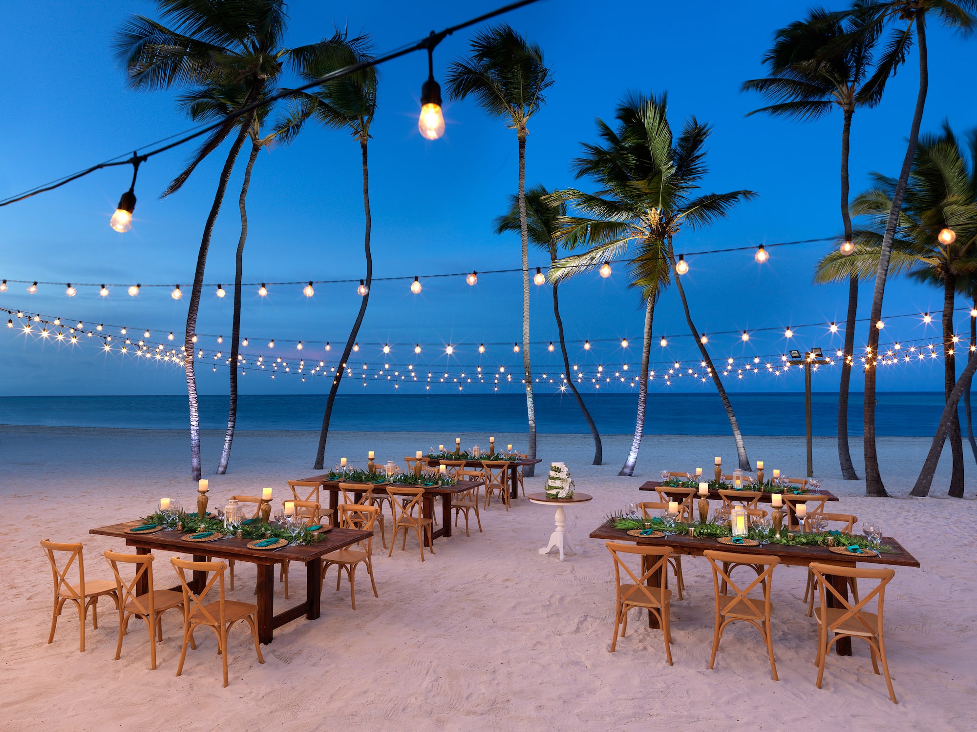 a beach with tables and chairs and palm trees