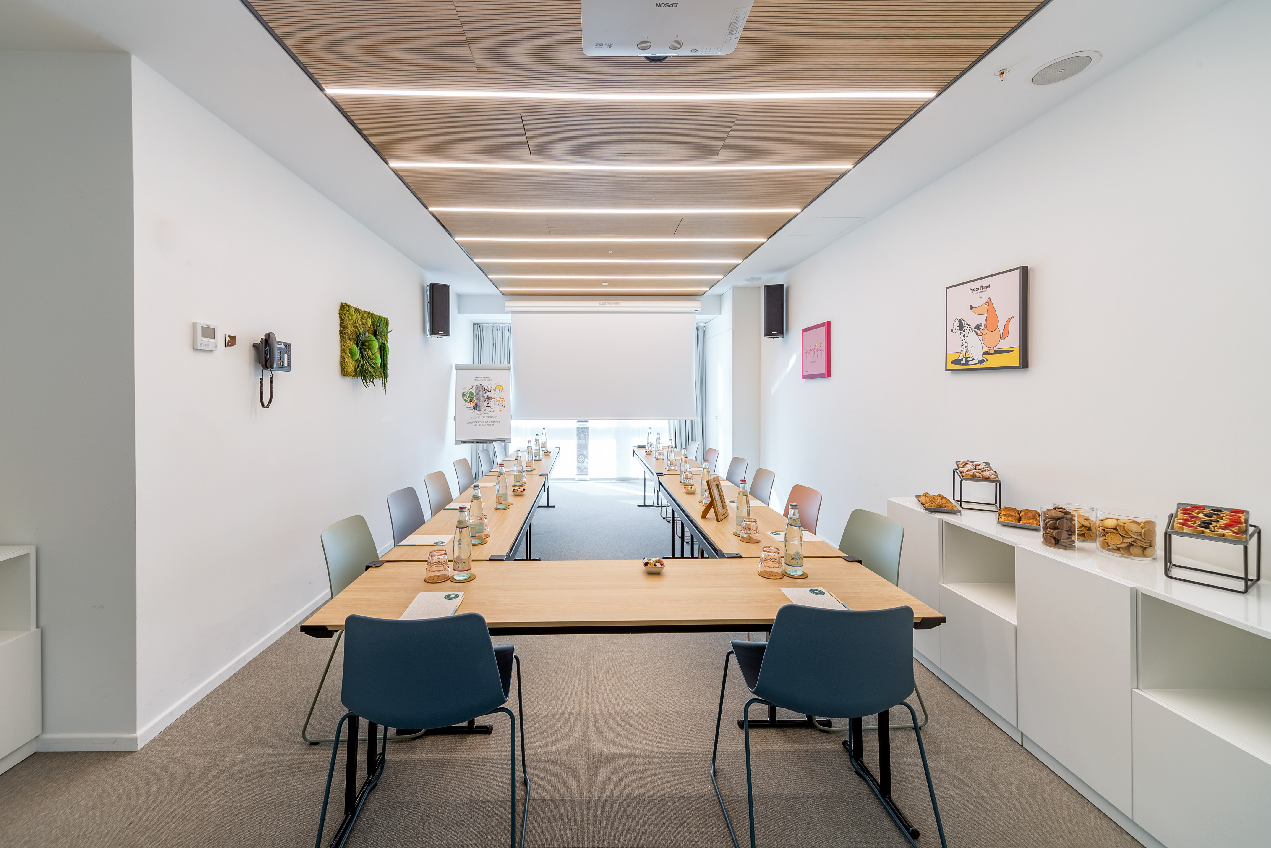 Sleek U-shaped conference room with projection screen and refreshments.