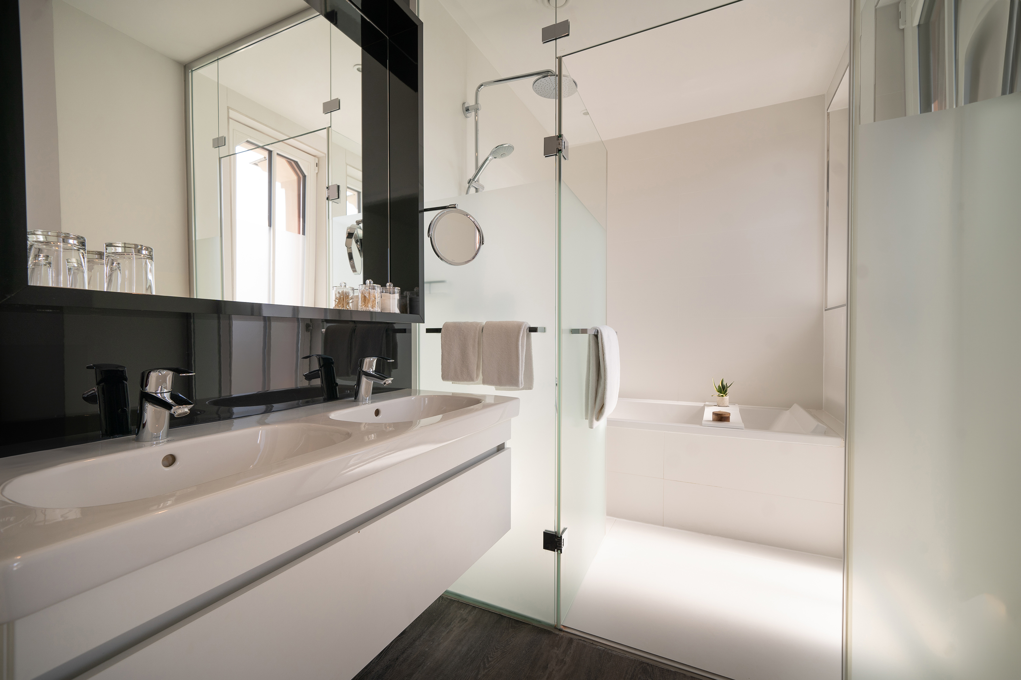 Modern bathroom with double vanity, walk-in glass shower, and bathtub.