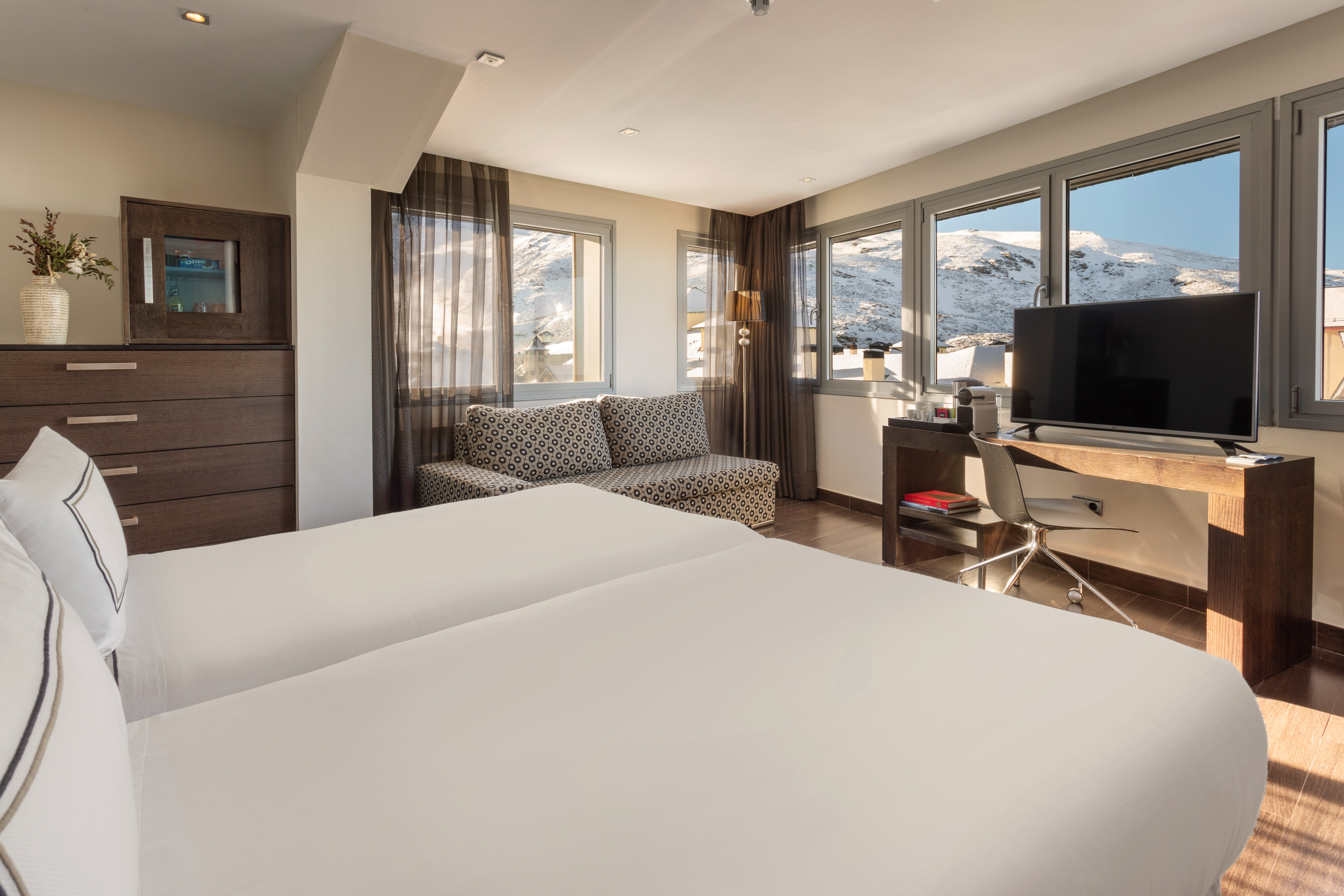 Ski resort twin room with sofa, desk, and snowy mountain views.