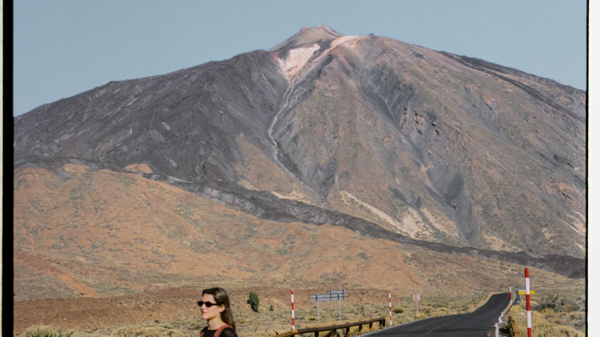 a woman walking on a road with a mountain in the background