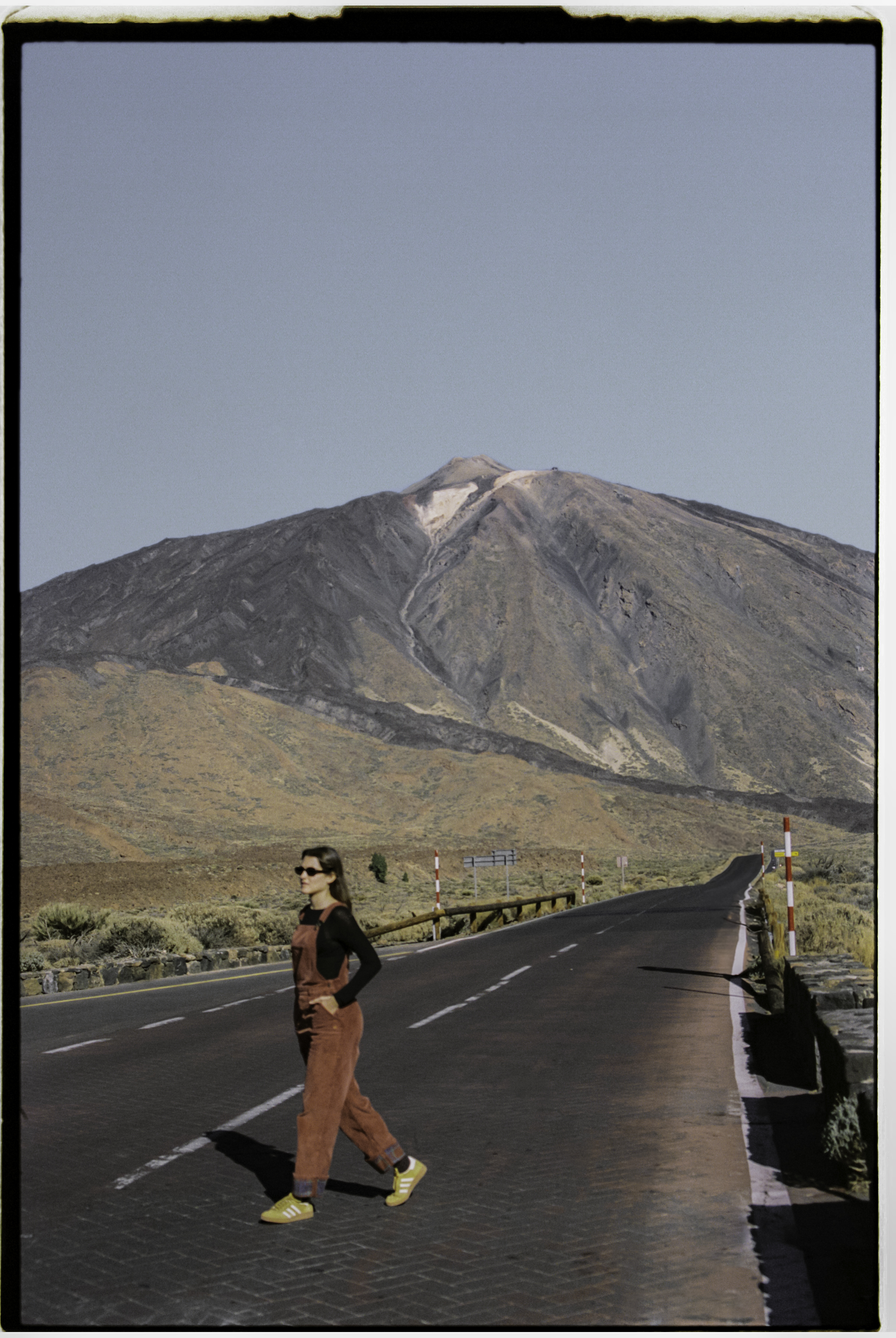 a woman walking on a road with a mountain in the background