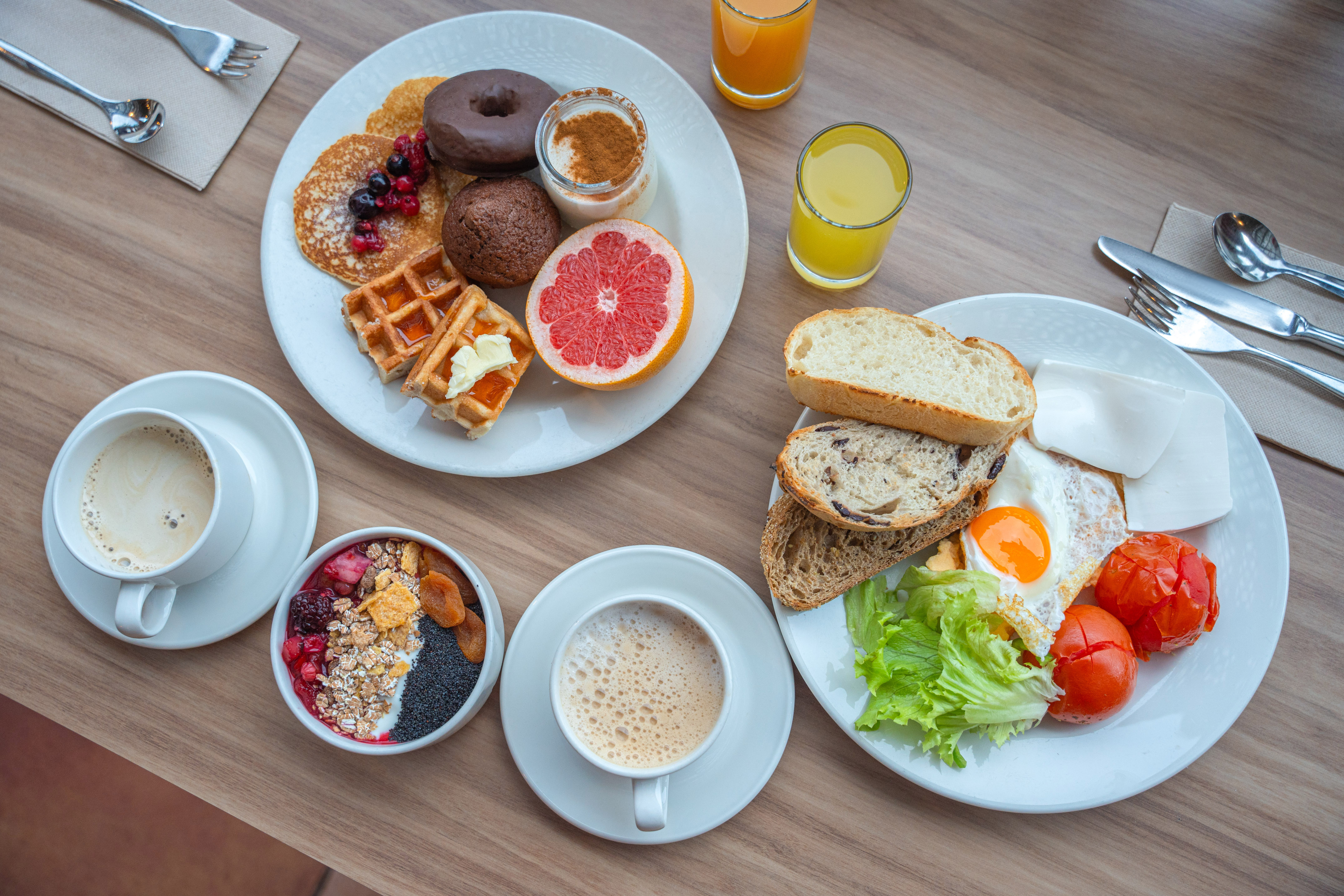 Breakfast spread: pancakes, waffles, fried egg, fruit, coffee, juice, and cereal.