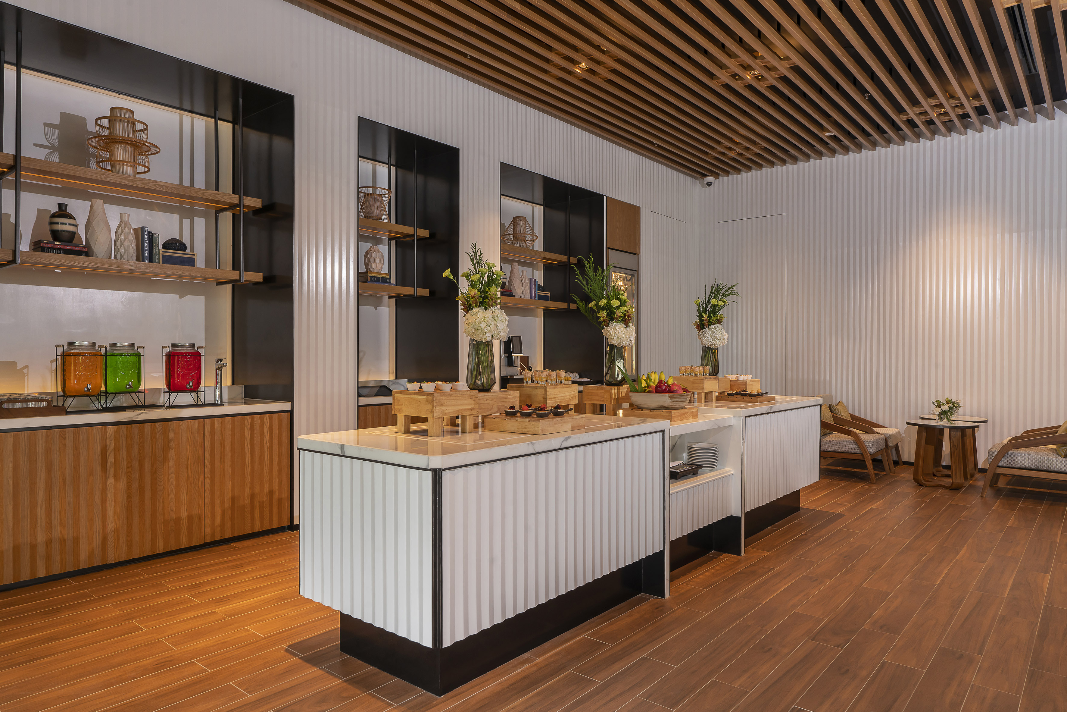 Modern hotel lounge buffet with fresh juices, pastries, fruits, and sleek design.