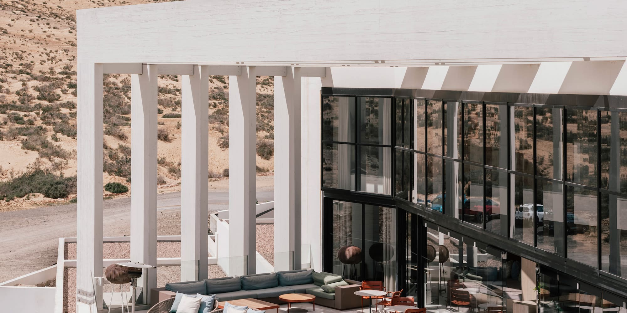 Modern outdoor terrace with lounge seating, fire pit, and desert backdrop.