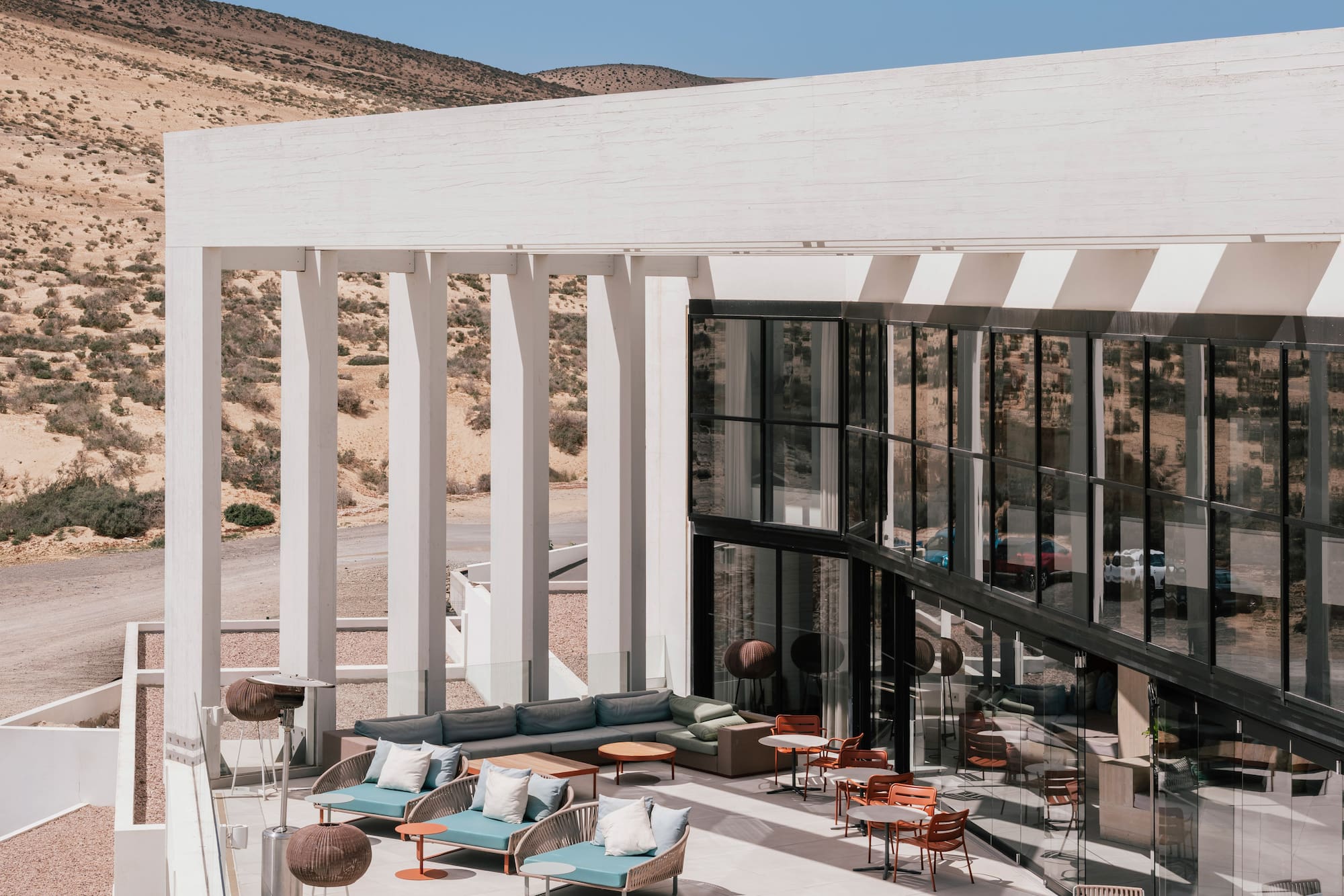 Modern outdoor terrace with lounge seating, fire pit, and desert backdrop.