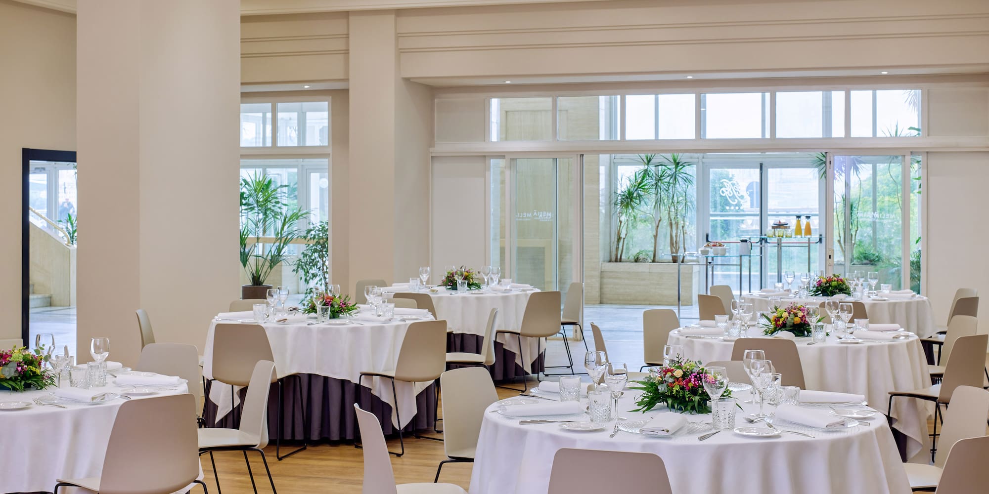 Elegant banquet hall with round tables set for a formal event, natural light.