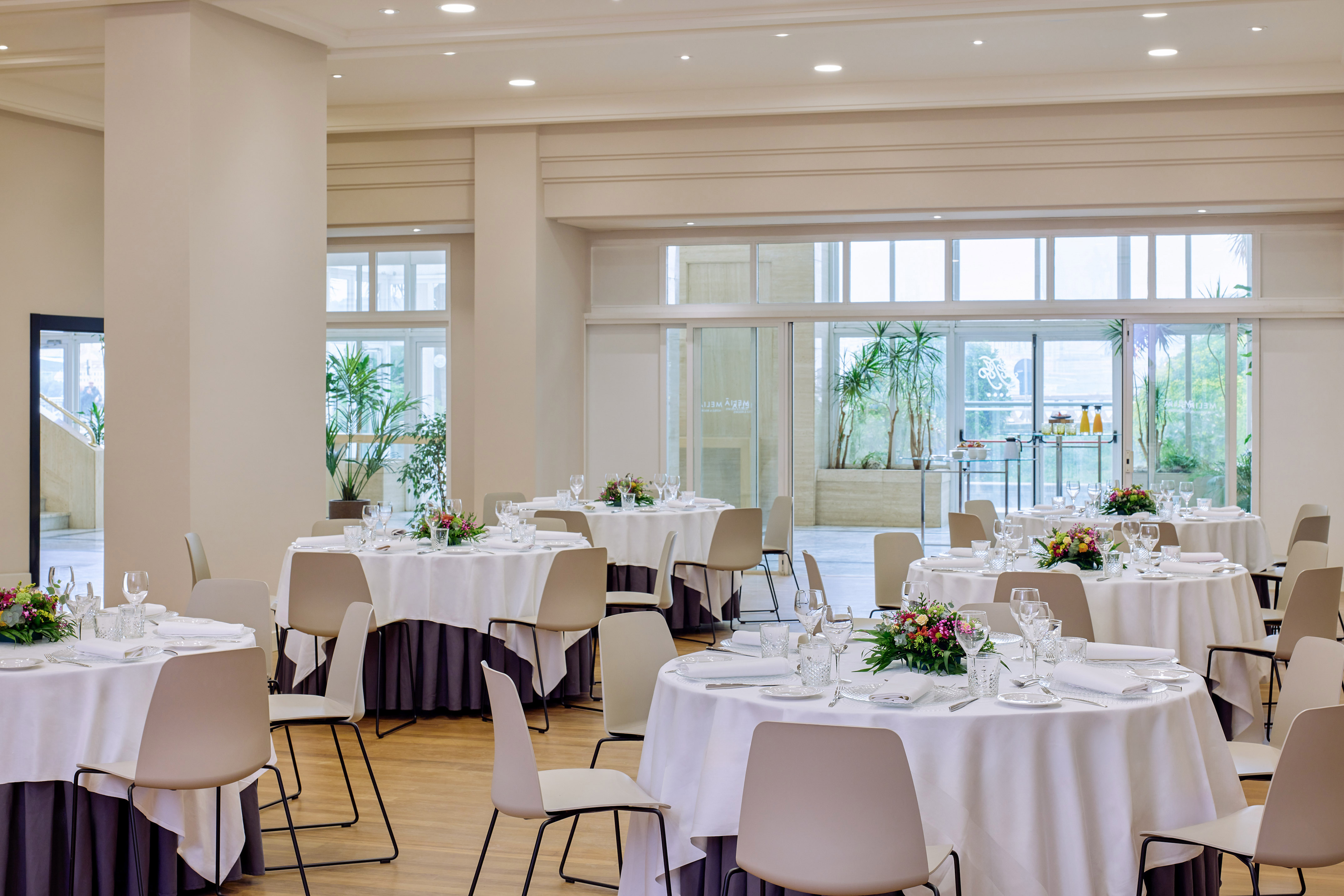 Elegant banquet hall with round tables set for a formal event, natural light.