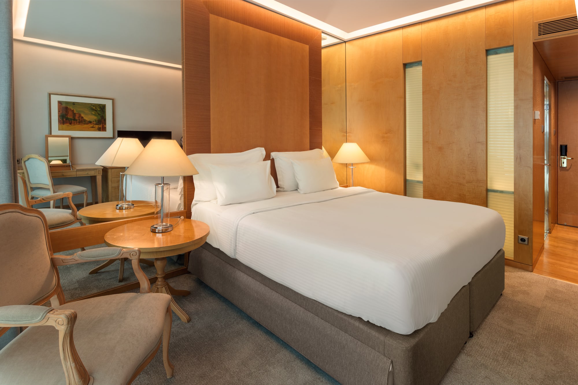 Elegant hotel bedroom with king bed, wooden accents, and soft, warm lighting.