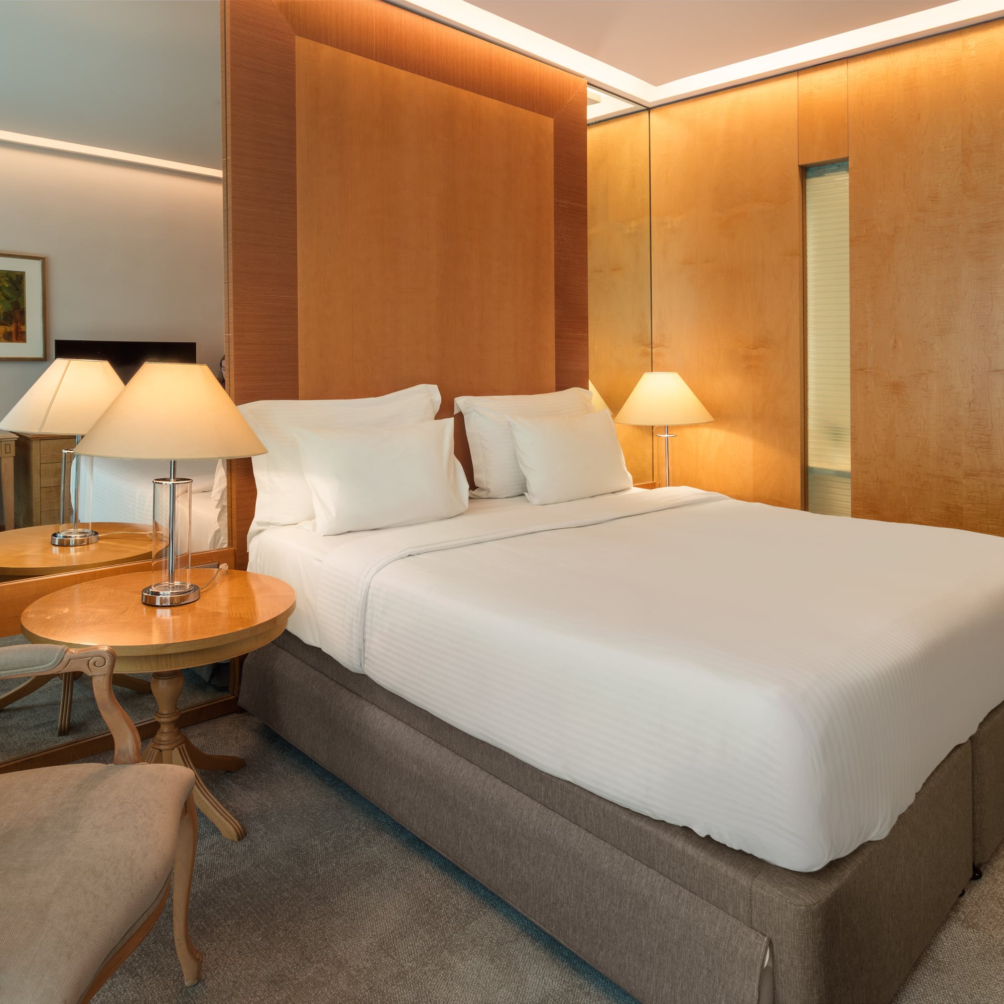 Elegant hotel bedroom with king bed, wooden accents, and soft, warm lighting.