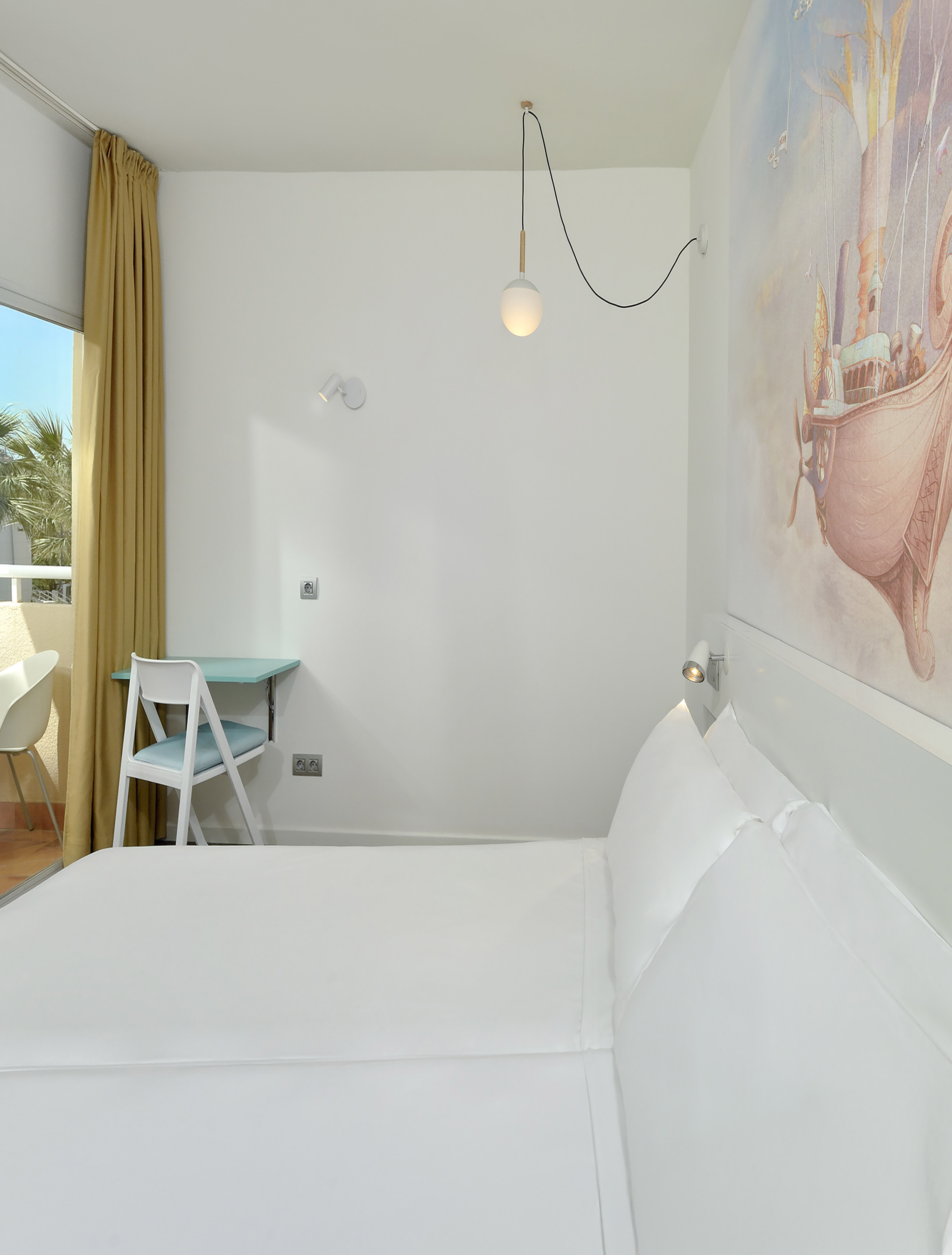 Modern hotel room with white bed, light blue desk, balcony, and wall mural.
