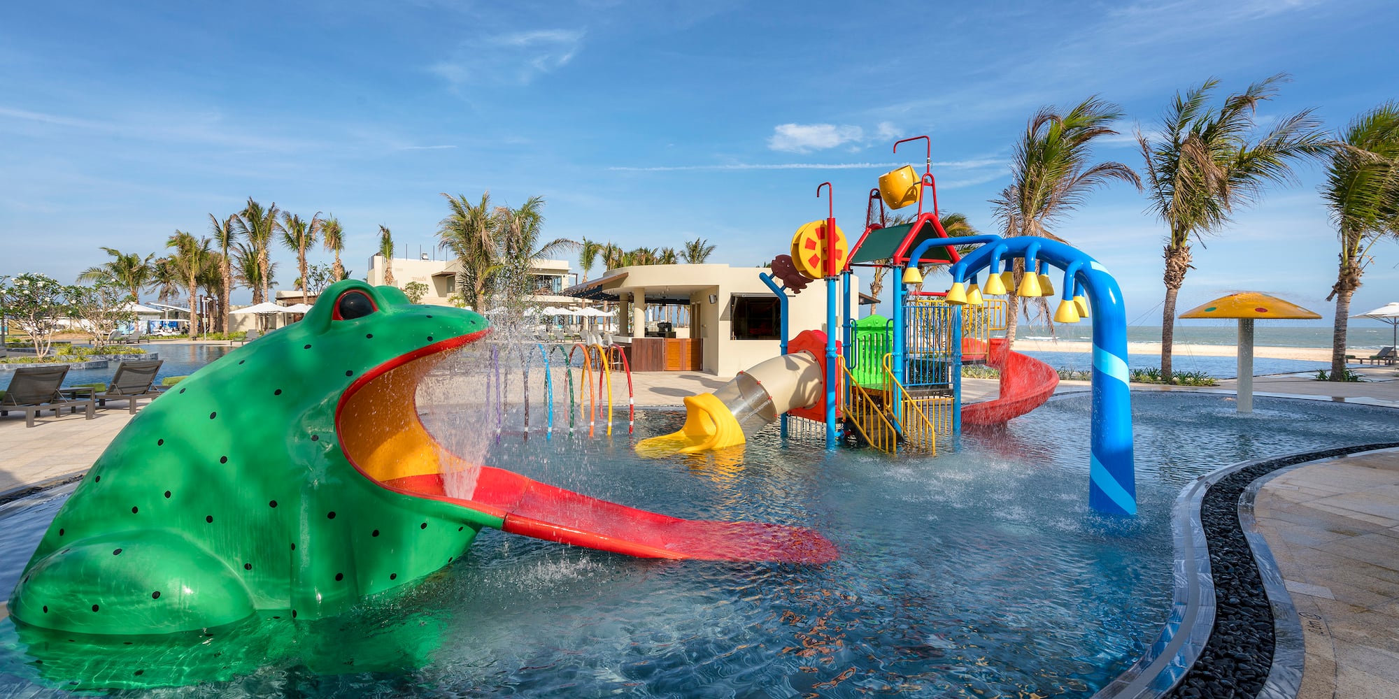 a water park with a large green frog and a slide