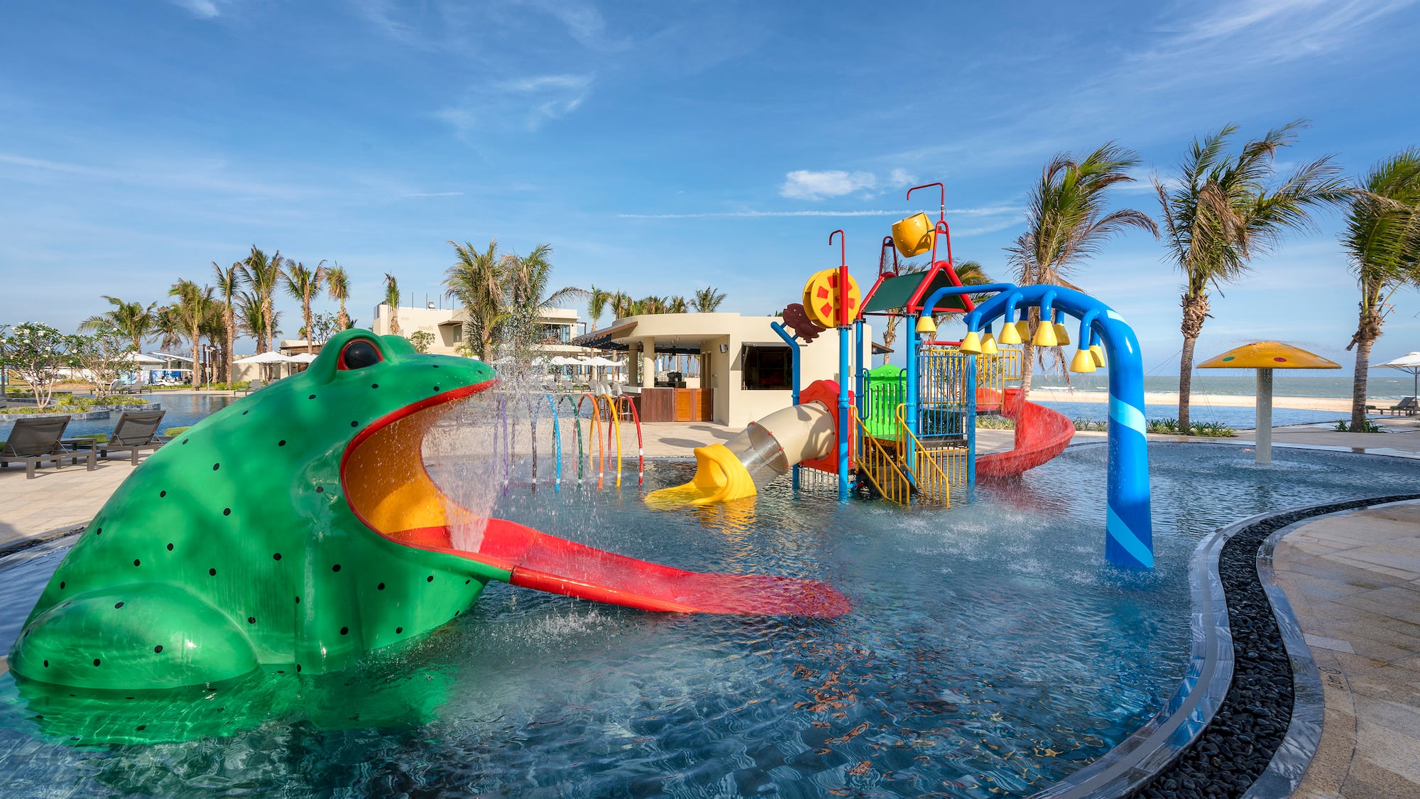 a water park with a large green frog and a slide