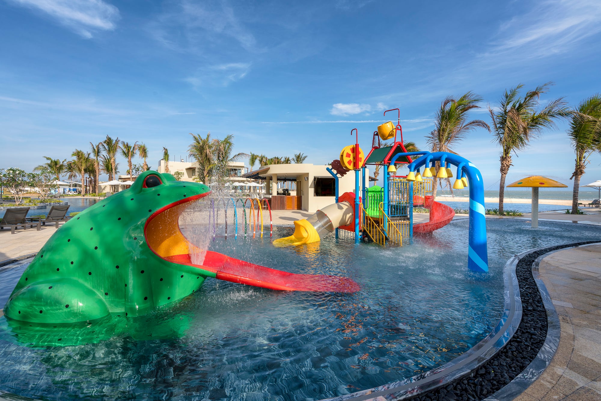 a water park with a large green frog and a slide