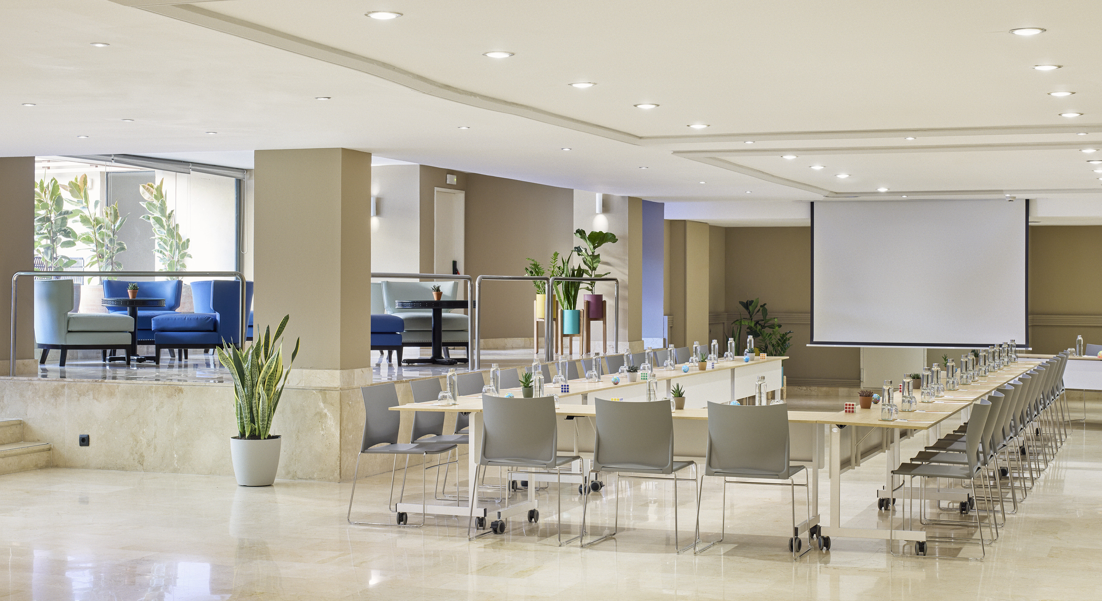 Modern conference room with tables, screen, and adjacent lounge area.