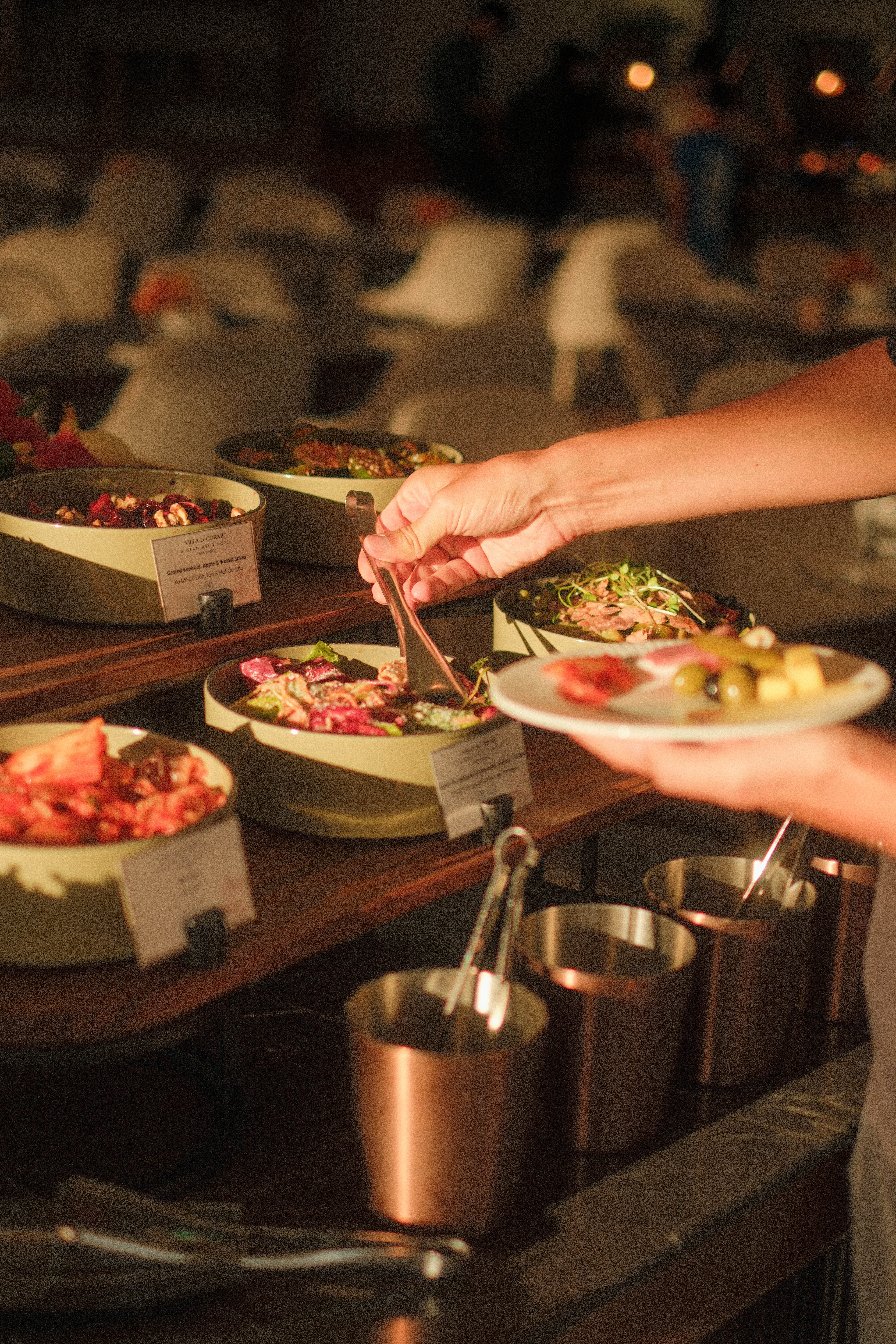 Hand serving Grated Beetroot, Apple & Walnut Salad from a hotel buffet.