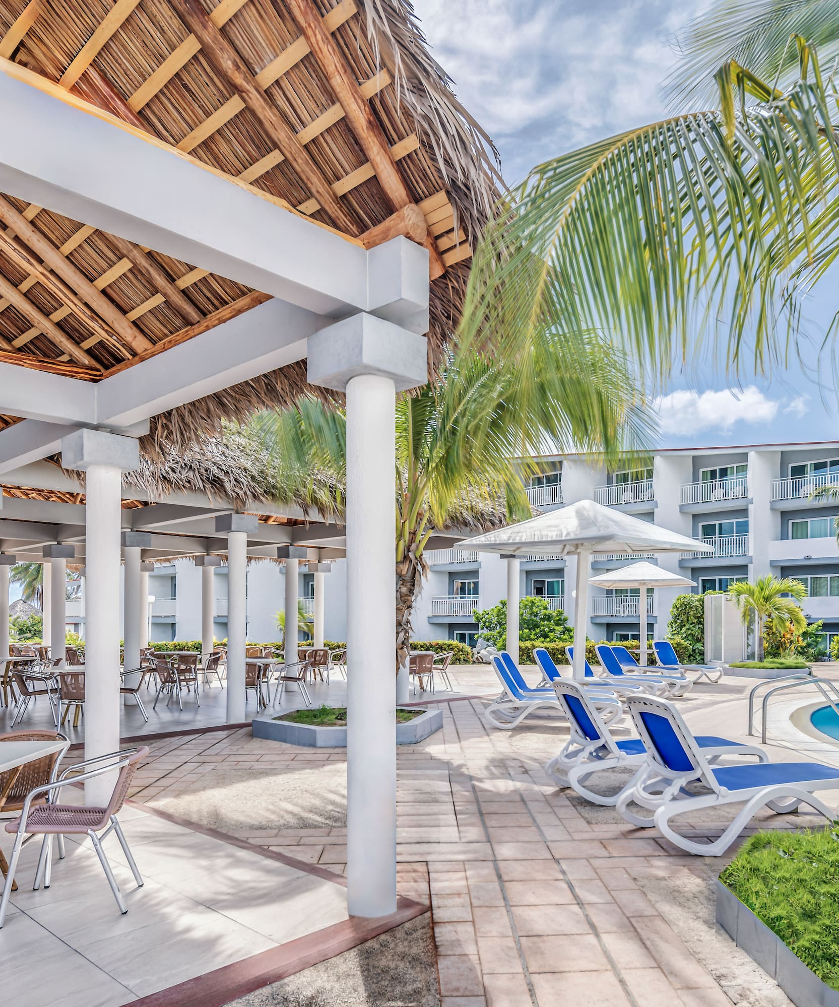 a pool with chairs and a thatched roof
