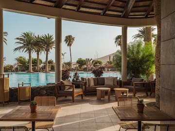 a patio with chairs and tables and a pool